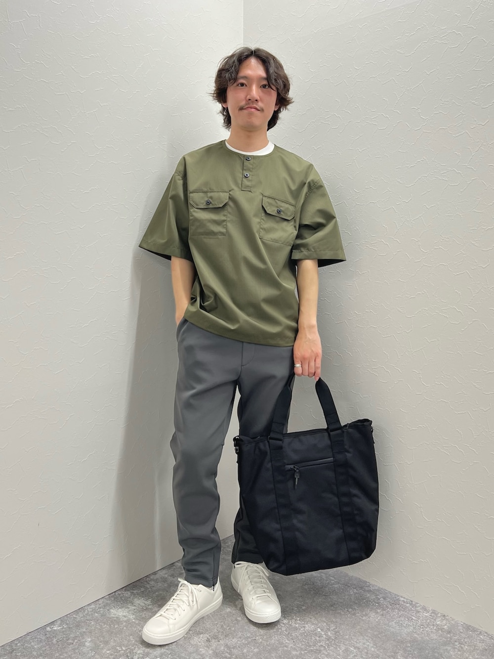 グリーン系のTシャツ/カットソー、ブラック系のトートバッグ、グレー系のその他パンツを着用したメンズの春コーディネートの2枚目の写真
