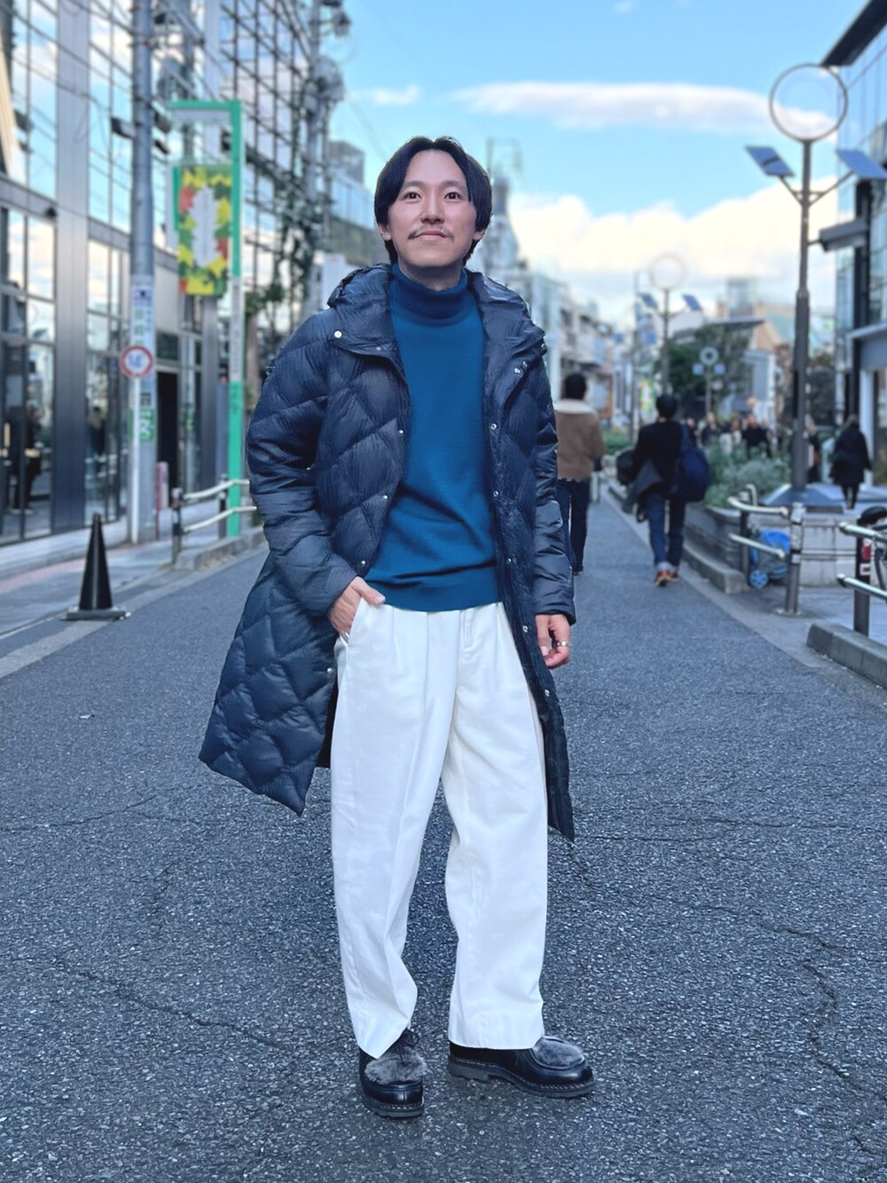 グレー系のダウンジャケット/コート、ブルー系のニット/セーター、ホワイト系のデニムパンツを着用したメンズの冬コーディネートの2枚目の写真