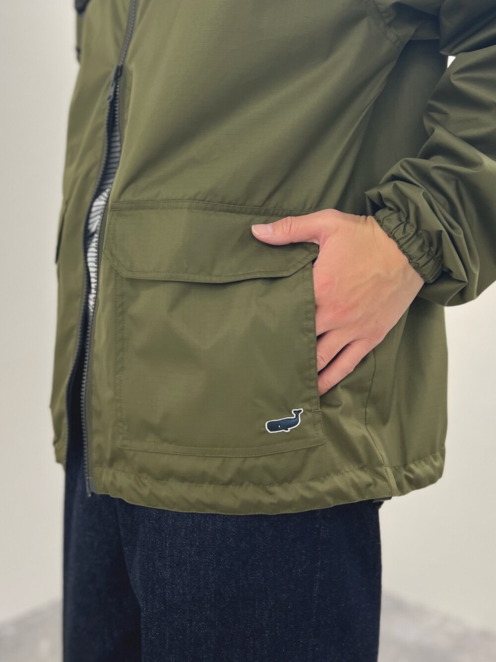 グリーン系のブルゾン、ホワイト系のTシャツ/カットソー、ブルー系のデニムパンツを着用したメンズの冬コーディネートの9枚目の写真