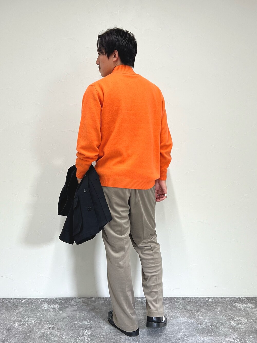 オレンジ系のニット/セーター、ブラック系のミリタリージャケット、ベージュ系のその他パンツを着用したメンズの秋コーディネートの7枚目の写真