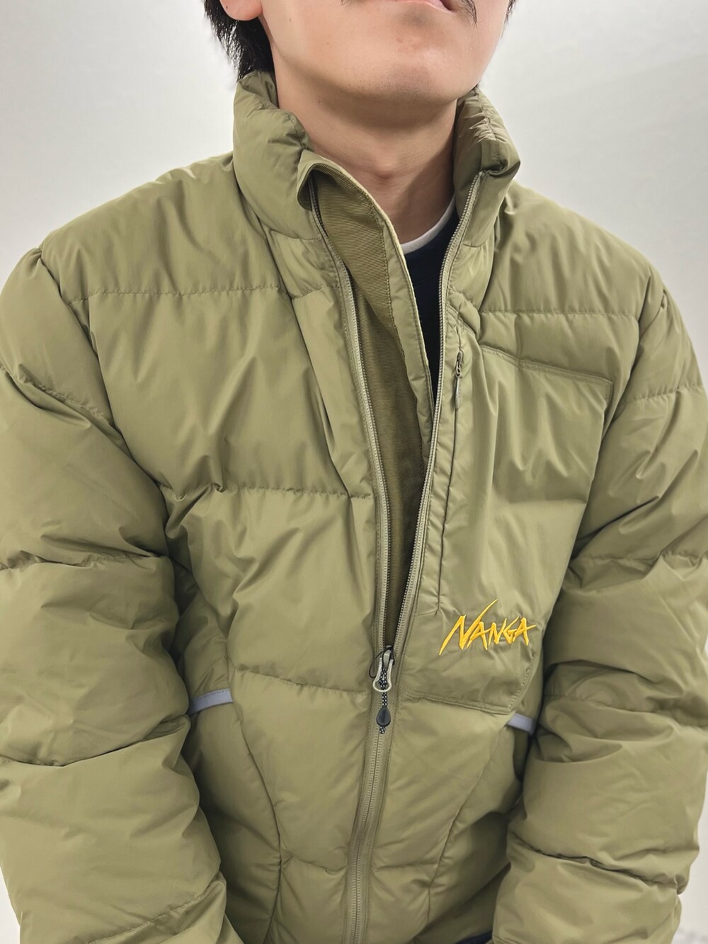 グリーン系のダウンジャケット/コート、ブルー系のTシャツ/カットソー、グレー系のその他パンツを着用したメンズの秋コーディネートの6枚目の写真