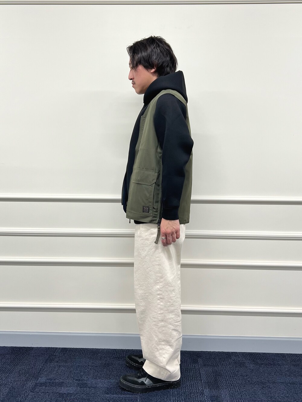 グリーン系のベスト、ブラック系のパーカー、ホワイト系のデニムパンツを着用したメンズの冬コーディネートの7枚目の写真