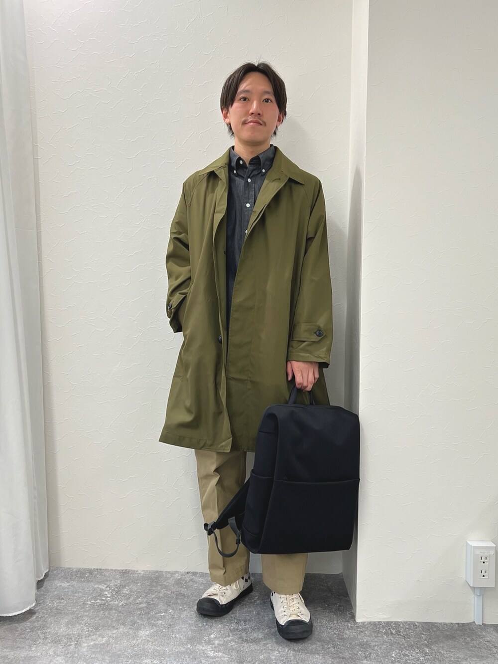 グリーン系のステンカラーコート、ブラック系のシャツ/ブラウス、ブラック系のバックパック/リュックを着用したメンズの春コーディネートの3枚目の写真