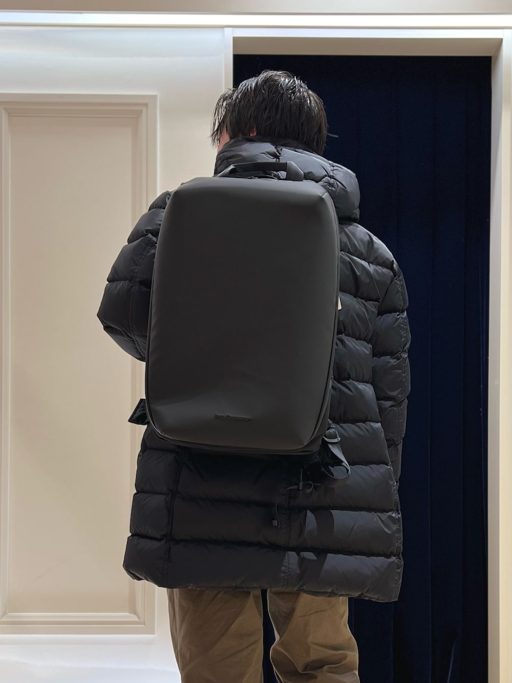 グレー系のテーラードジャケット、ブラック系のバックパック/リュック、ブラック系のダウンジャケット/コートを着用したメンズの冬コーディネートの7枚目の写真