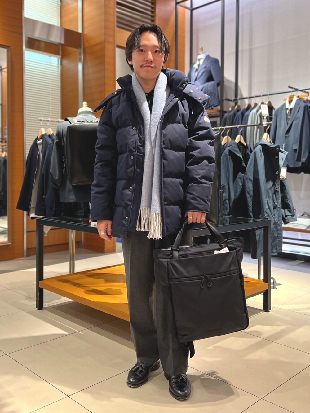 ブルー系のダウンジャケット/コート、ブラック系のトートバッグ、ブラック系のローファーを着用したメンズの冬コーディネートの3枚目の写真
