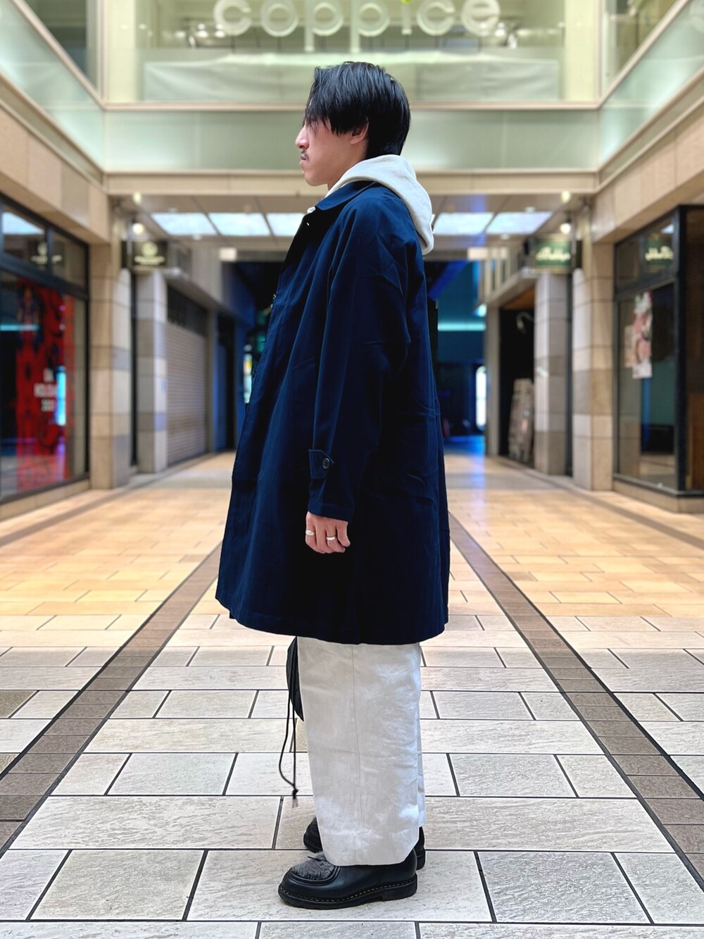 グレー系のパーカー、ブルー系のステンカラーコート、グレー系のトートバッグを着用したメンズの冬コーディネートの4枚目の写真