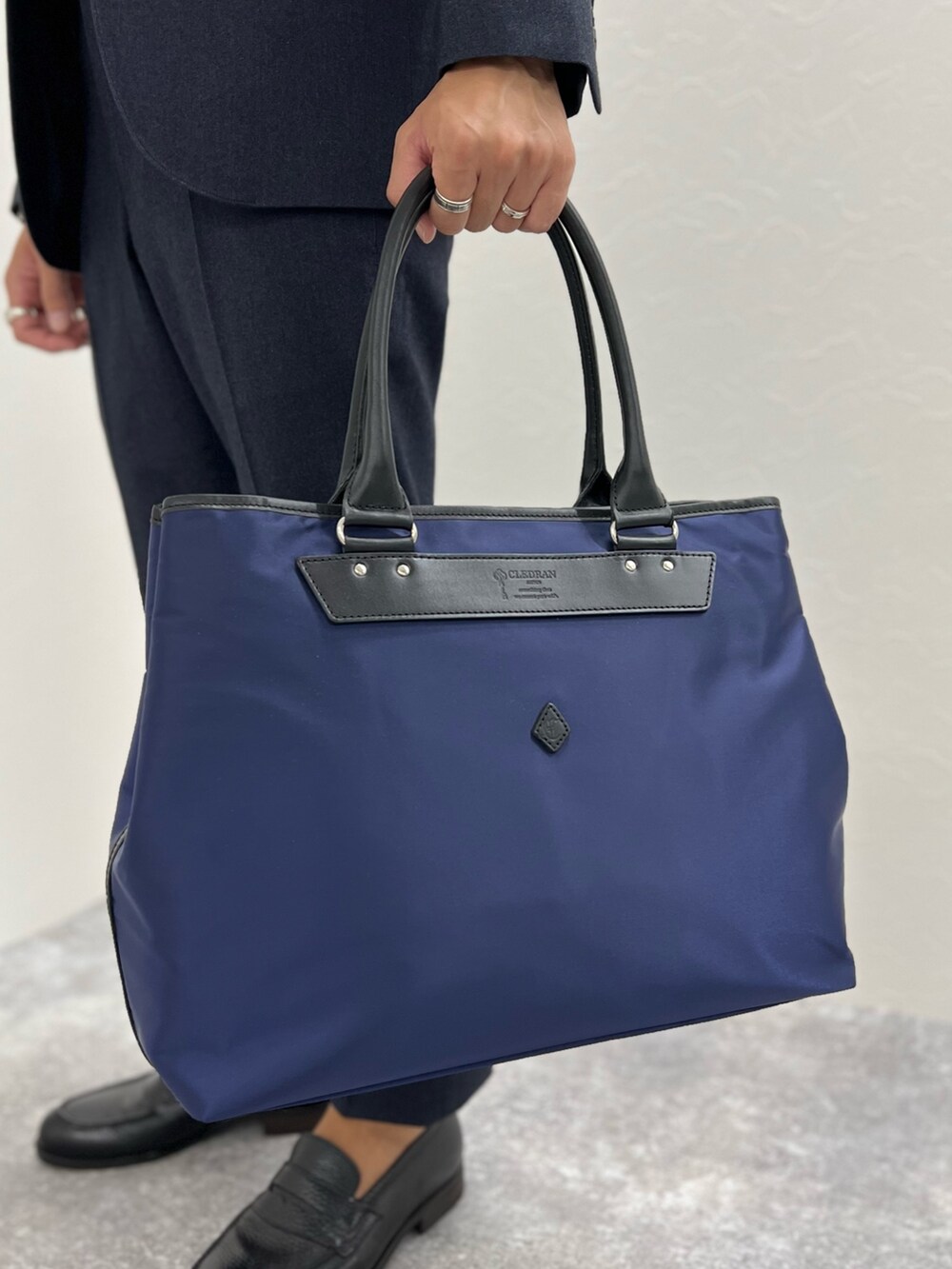 ブルー系のテーラードジャケット、ブルー系のその他パンツ、ブルー系のトートバッグを着用したメンズの秋コーディネートの7枚目の写真