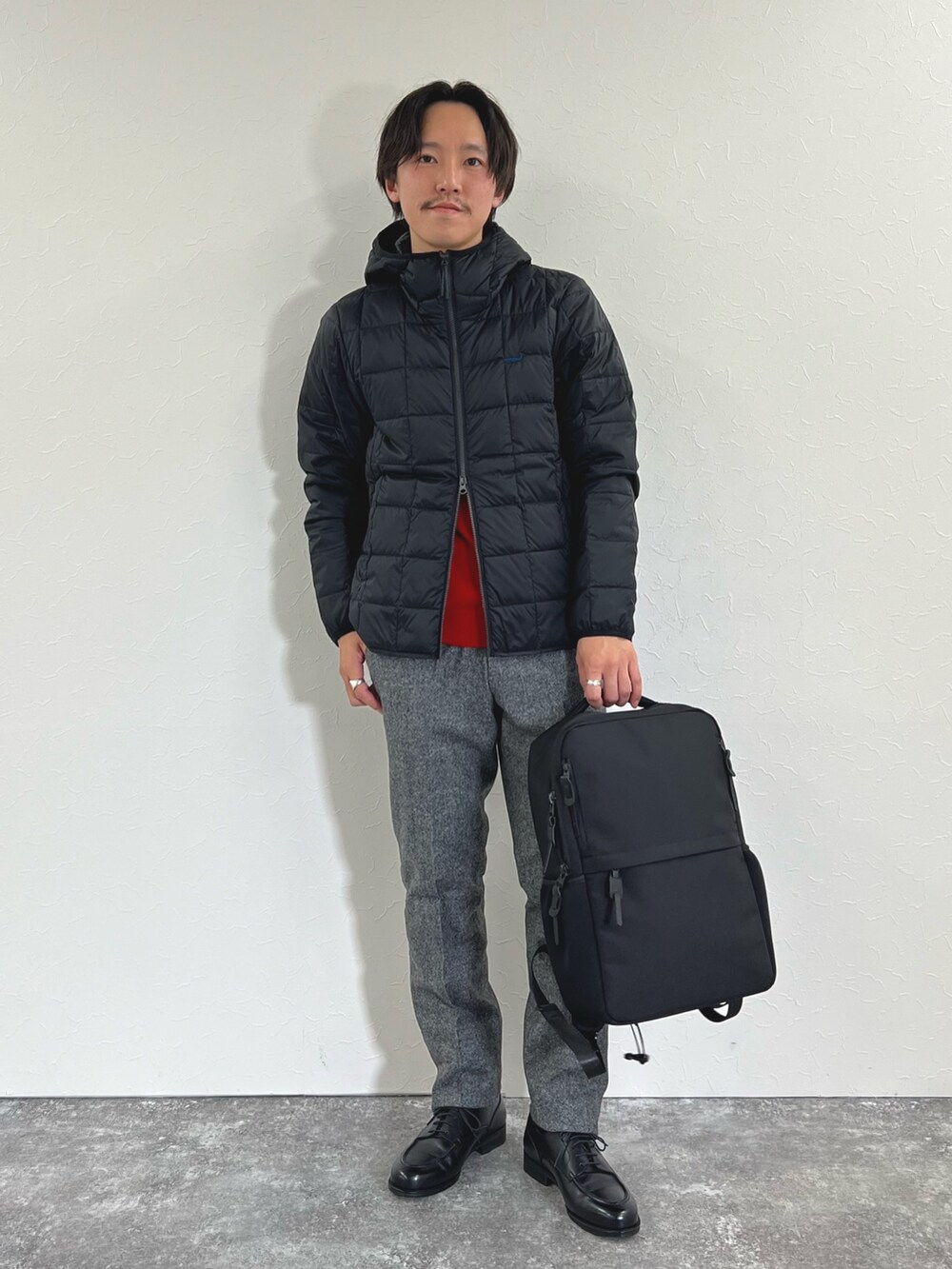 ブラック系のダウンジャケット/コート、レッド系のニット/セーター、グレー系のスラックスを着用したメンズの秋コーディネートの4枚目の写真