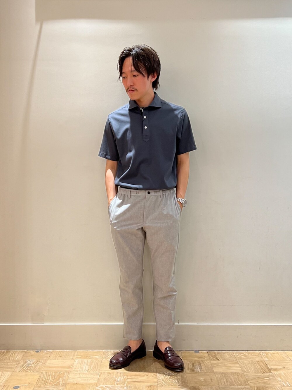 グレー系のポロシャツ、ベージュ系のその他パンツを着用したメンズの夏コーディネートの2枚目の写真