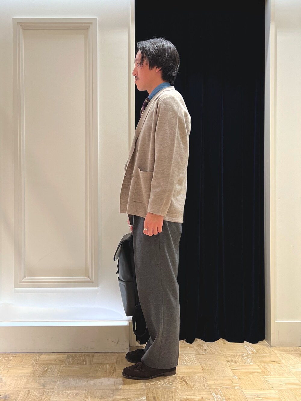 ベージュ系のテーラードジャケット、ブラック系のダウンベスト、ブラック系のバックパック/リュックを着用したメンズの冬コーディネートの7枚目の写真