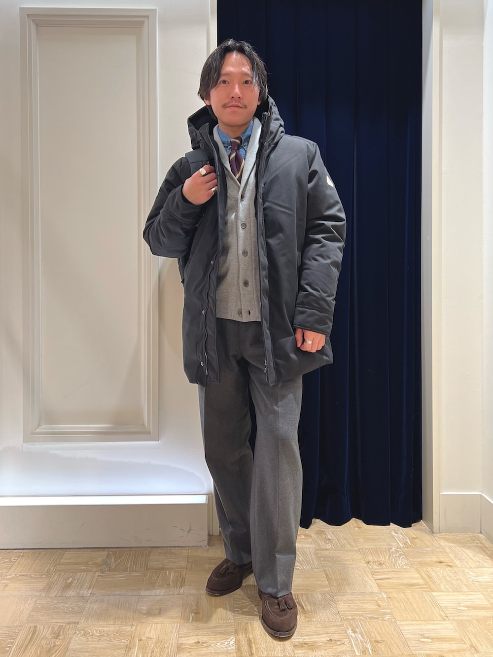 ブラック系のダウンジャケット/コート、グレー系のカーディガン/ボレロ、ブラック系のバックパック/リュックを着用したメンズの冬コーディネートの2枚目の写真