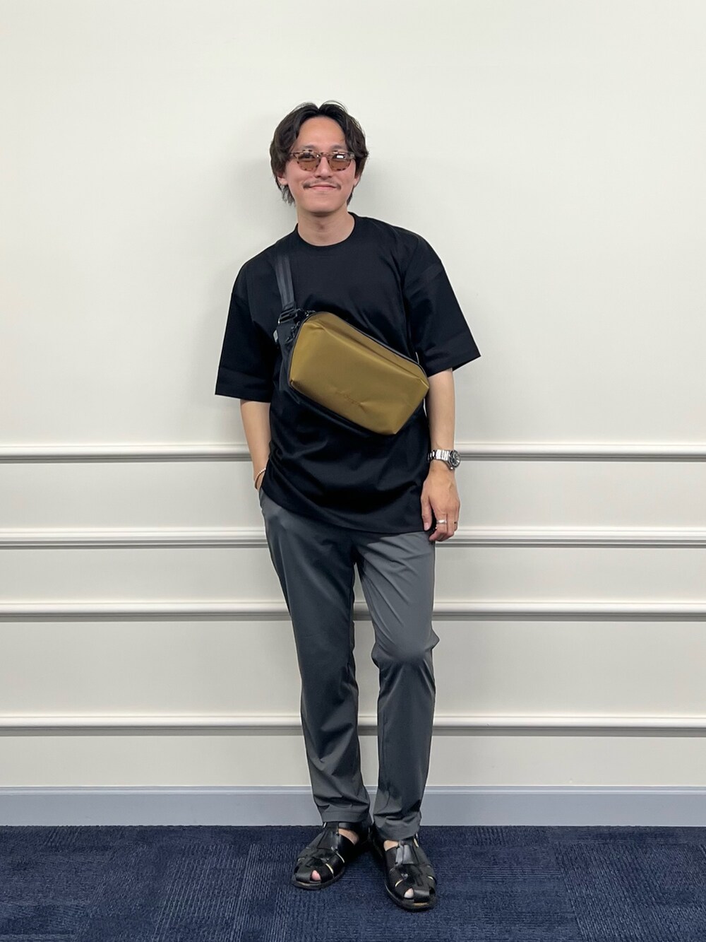 ブラック系のTシャツ/カットソー、グリーン系のショルダーバッグ、グレー系のその他パンツを着用したメンズの春コーディネートの2枚目の写真