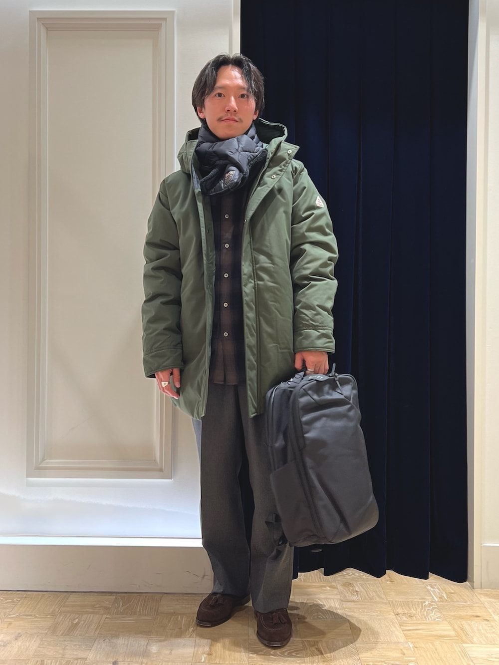 グリーン系のシャツ/ブラウス、ブラック系のバックパック/リュック、グリーン系のダウンジャケット/コートを着用したメンズの冬コーディネートの5枚目の写真