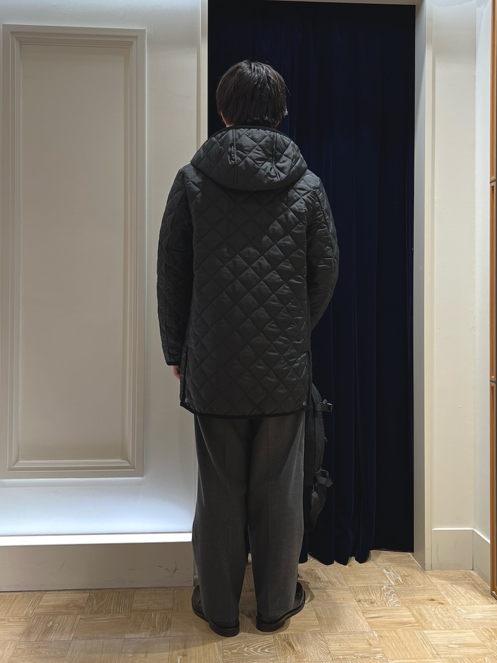 ブラック系のステンカラーコート、ブラック系のローファー、ブラック系のバックパック/リュックを着用したメンズの冬コーディネートの4枚目の写真