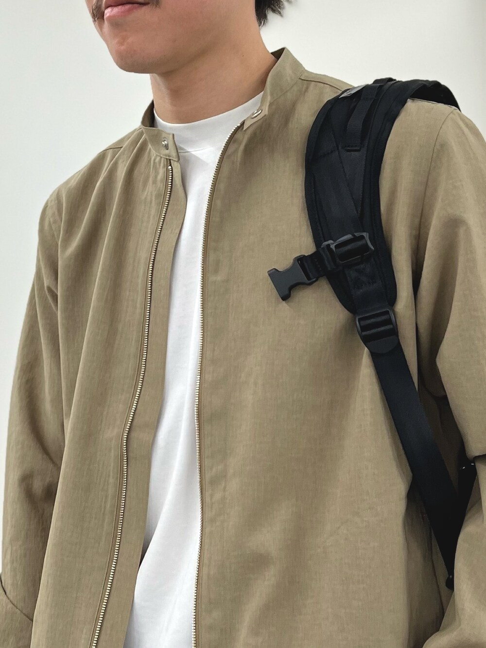 ホワイト系のTシャツ/カットソー、ベージュ系のブルゾン、ブラック系のバックパック/リュックを着用したメンズの春コーディネートの6枚目の写真