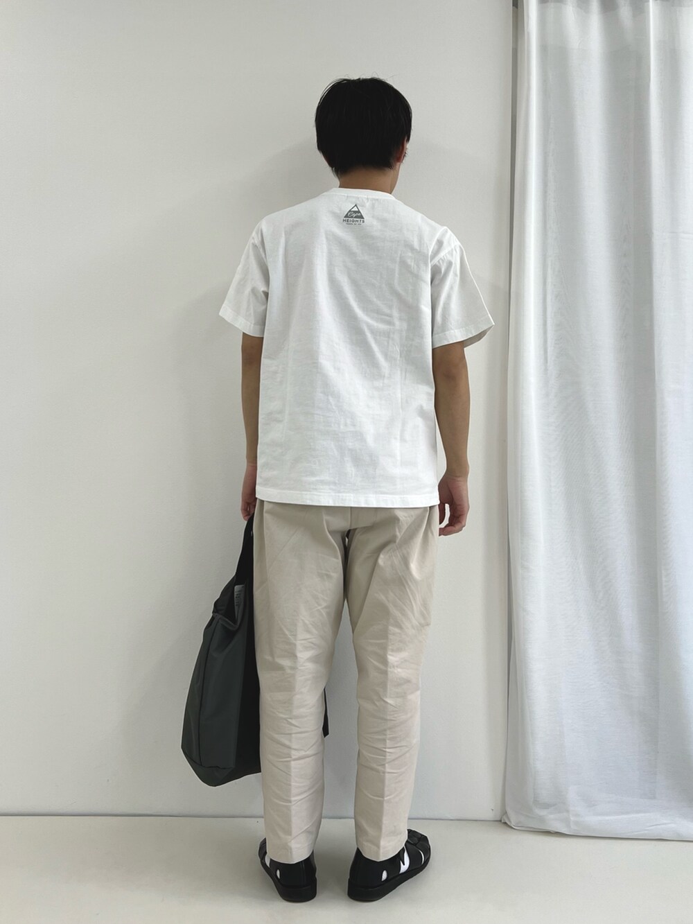 ホワイト系のTシャツ/カットソー、グレー系のトートバッグ、ブラック系のサンダルを着用したメンズの春コーディネートの5枚目の写真