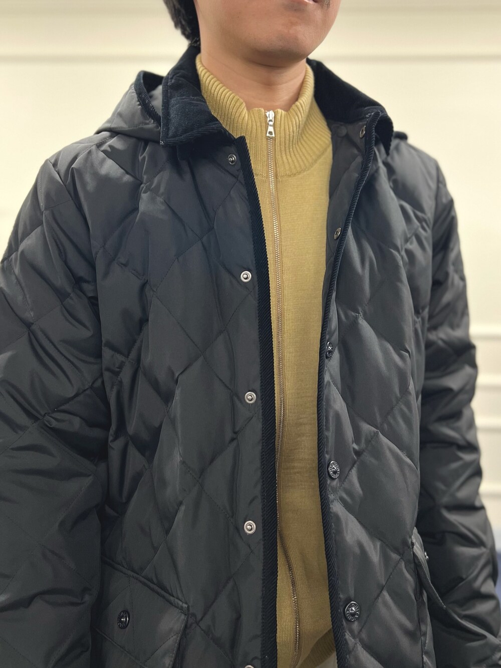 ブラック系のダウンジャケット/コート、ブラック系のバックパック/リュック、ベージュ系のカーディガン/ボレロを着用したメンズの冬コーディネートの9枚目の写真