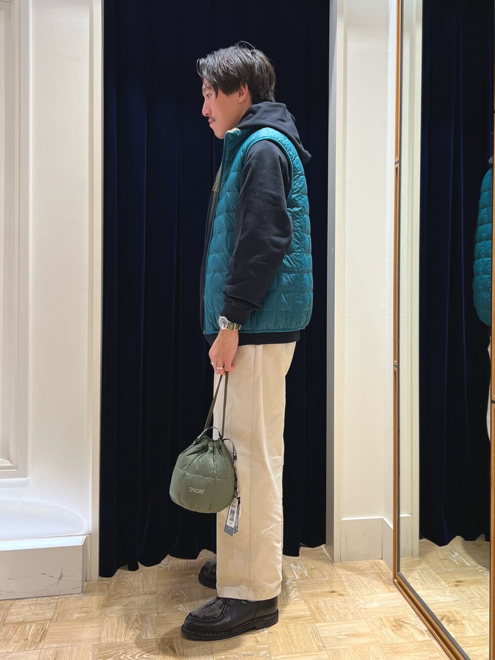 ブラック系のパーカー、グリーン系のダウンベスト、グリーン系のショルダーバッグを着用したメンズの秋コーディネートの3枚目の写真