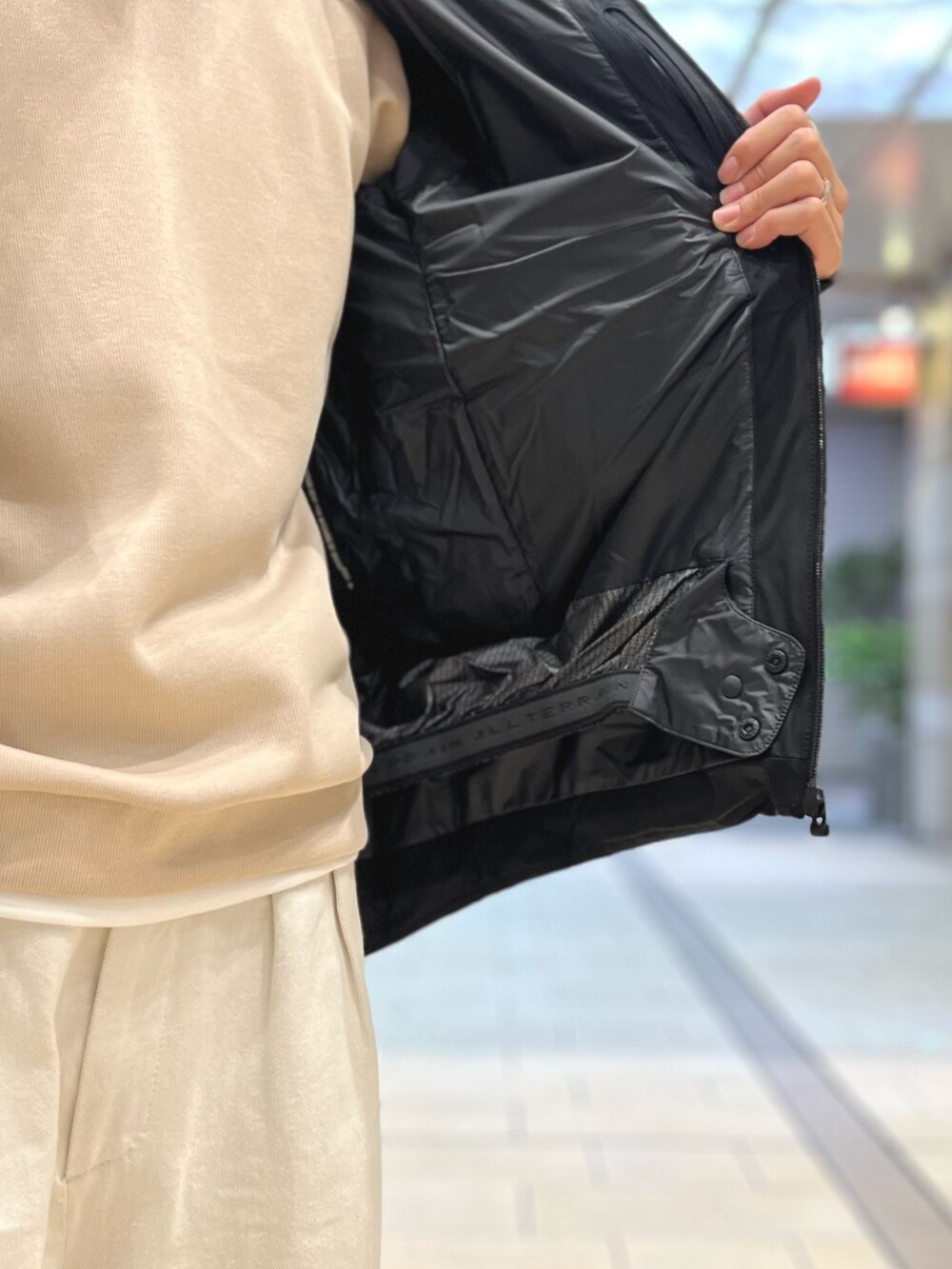 ベージュ系のトートバッグ、ベージュ系のTシャツ/カットソー、ブラック系のダウンジャケット/コートを着用したメンズの秋コーディネートの9枚目の写真
