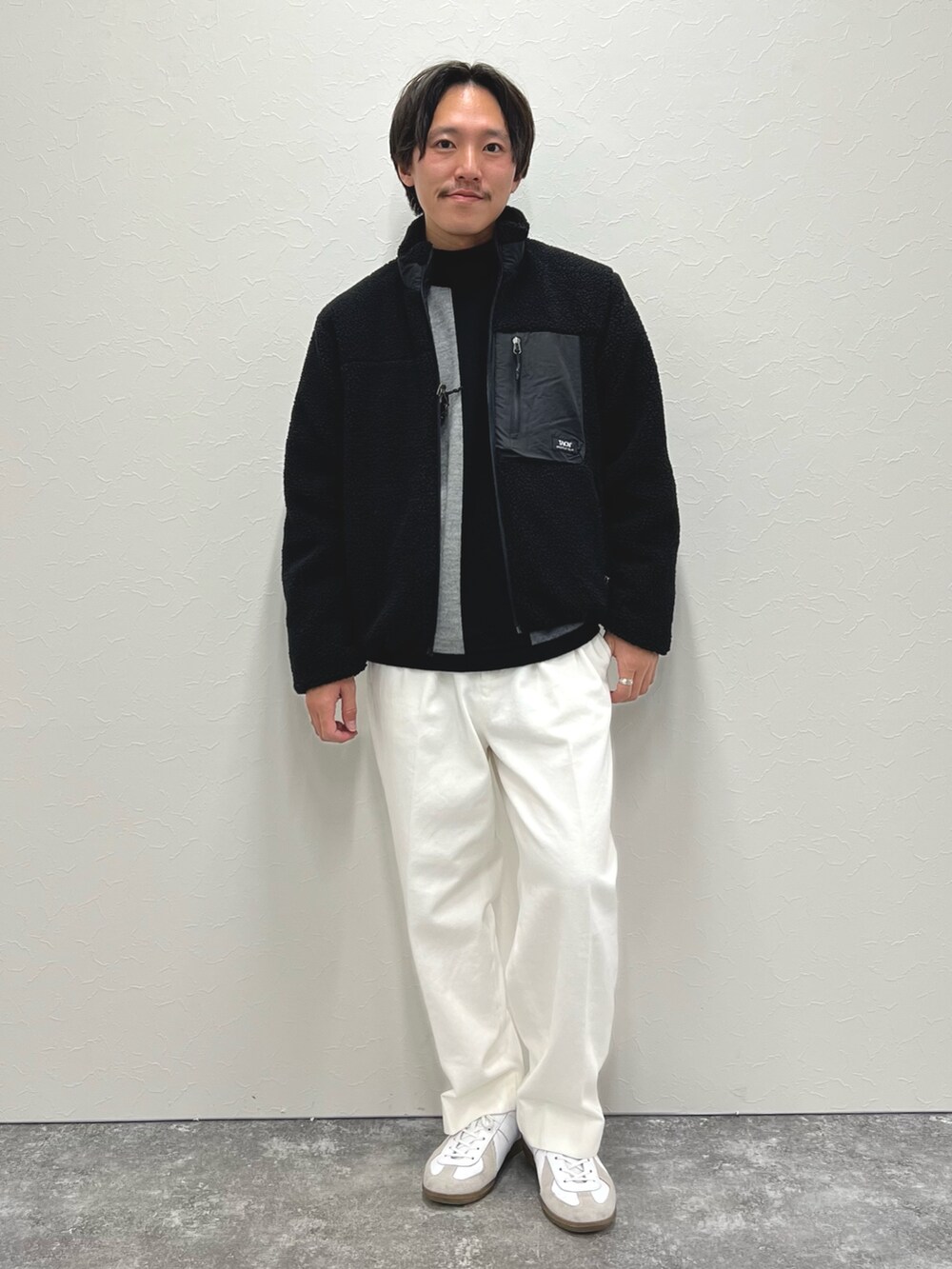 ブラック系のニット/セーター、ホワイト系のデニムパンツ、ブラック系のブルゾンを着用したメンズの冬コーディネートの2枚目の写真