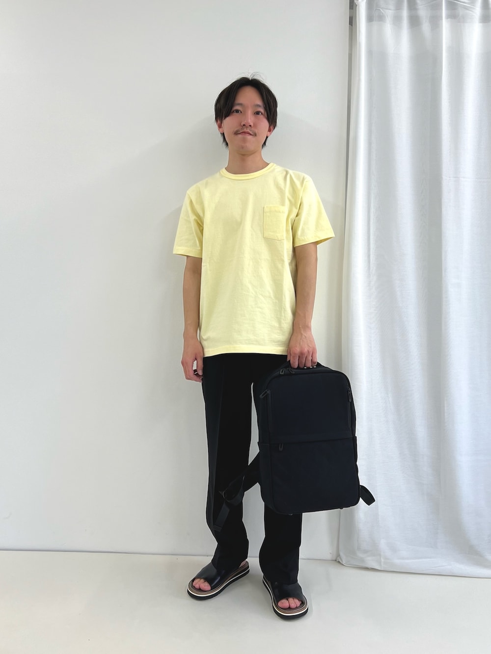イエロー系のTシャツ/カットソー、ブルー系のその他パンツ、ブラック系のバックパック/リュックを着用したメンズの春コーディネートの2枚目の写真