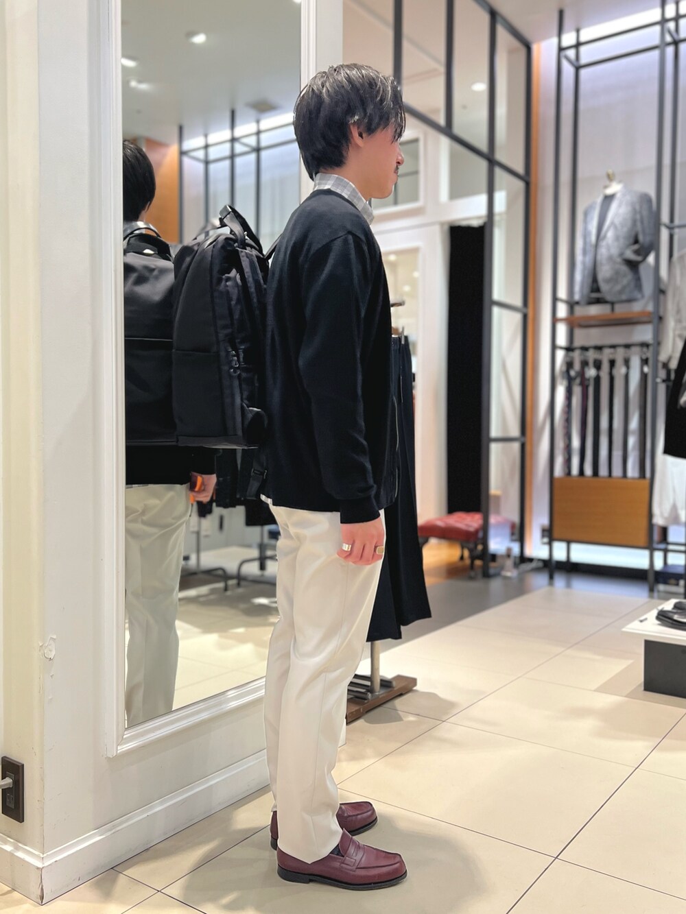 ブラック系のカーディガン/ボレロ、ブラック系のバックパック/リュック、ホワイト系のチノパンツを着用したメンズの冬コーディネートの5枚目の写真