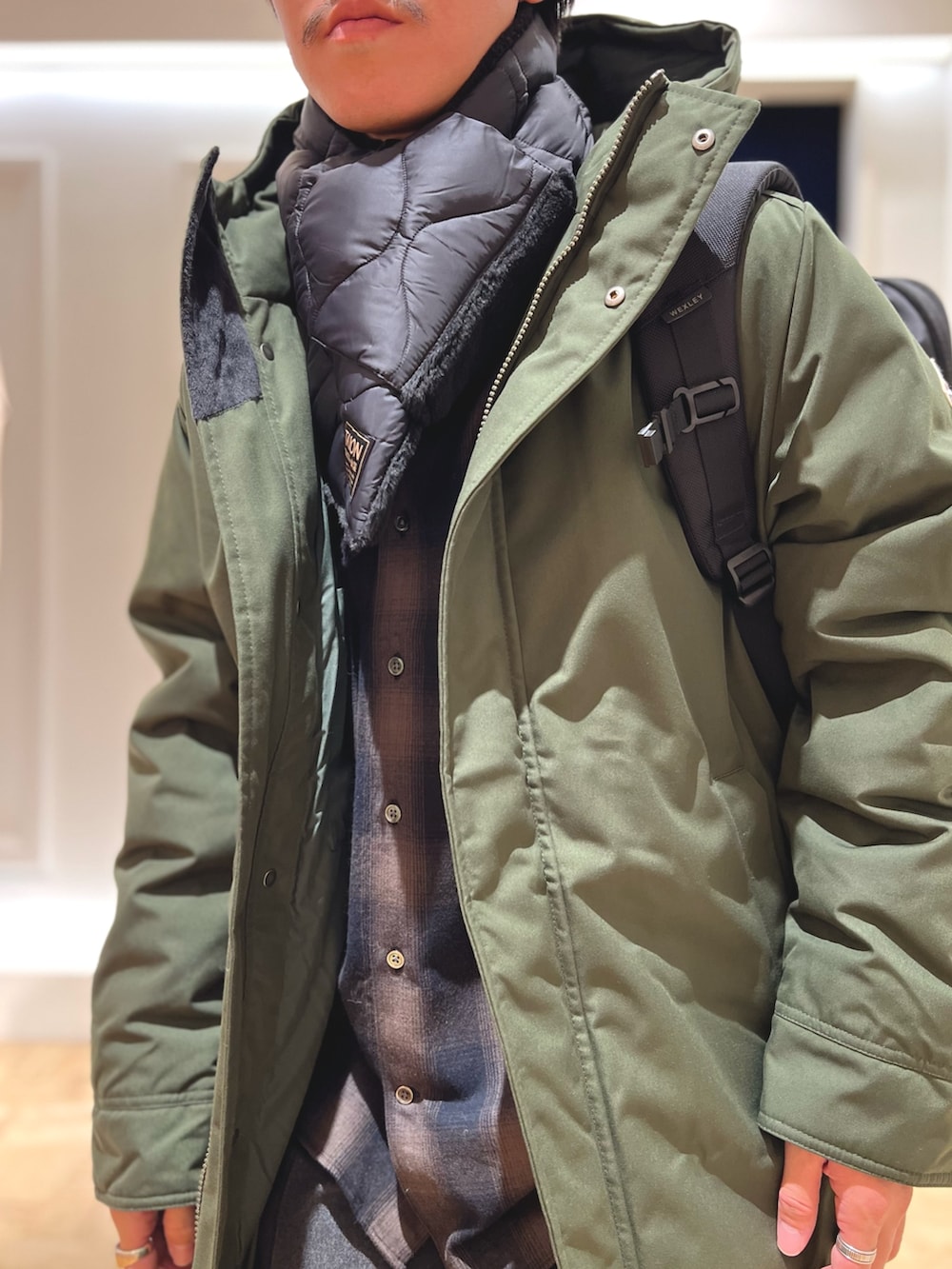 グリーン系のシャツ/ブラウス、ブラック系のバックパック/リュック、グリーン系のダウンジャケット/コートを着用したメンズの冬コーディネートの8枚目の写真