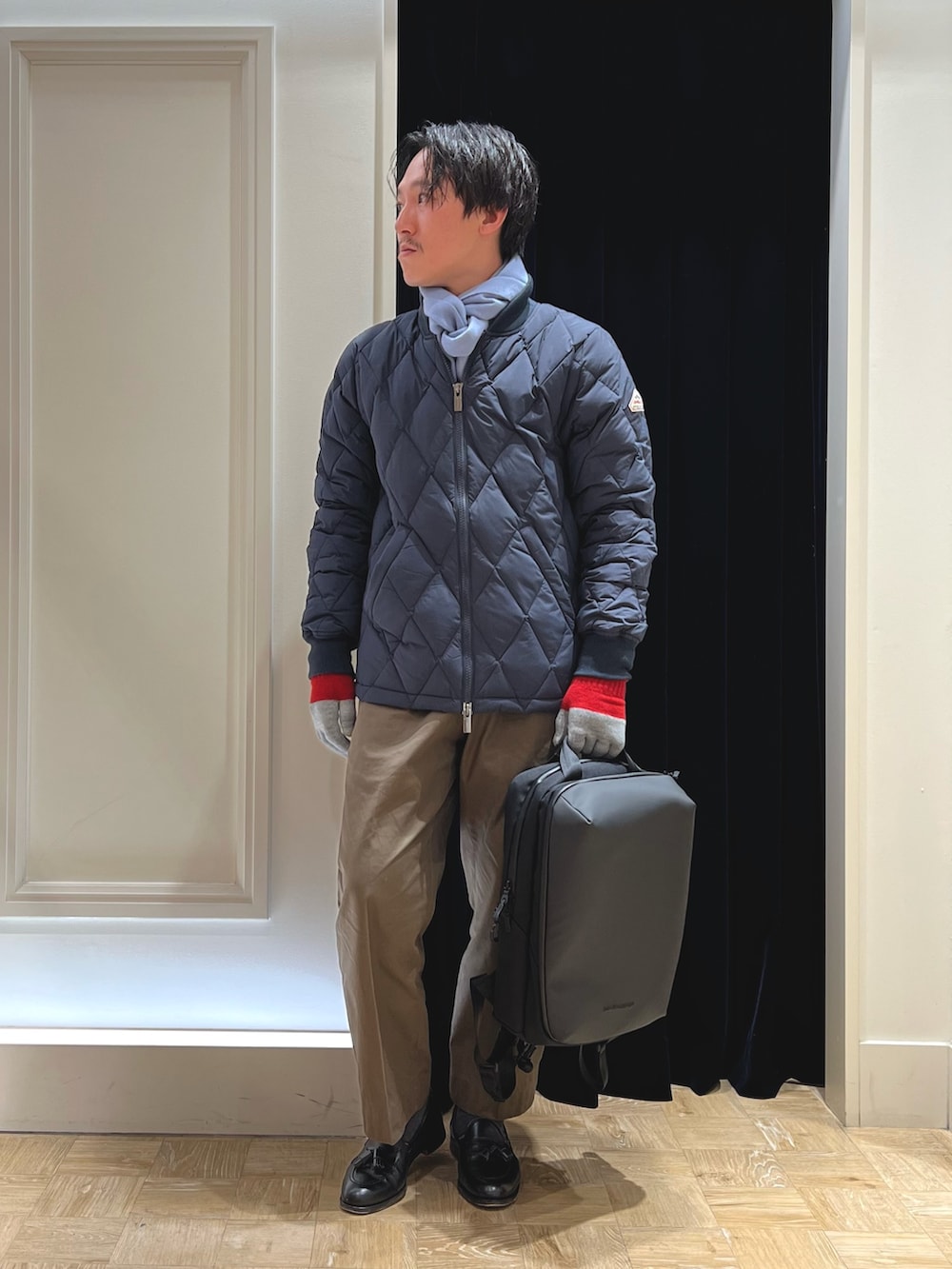 ブルー系のダウンジャケット/コート、ブラック系のバックパック/リュック、ブルー系のマフラーを着用したメンズの冬コーディネートの2枚目の写真