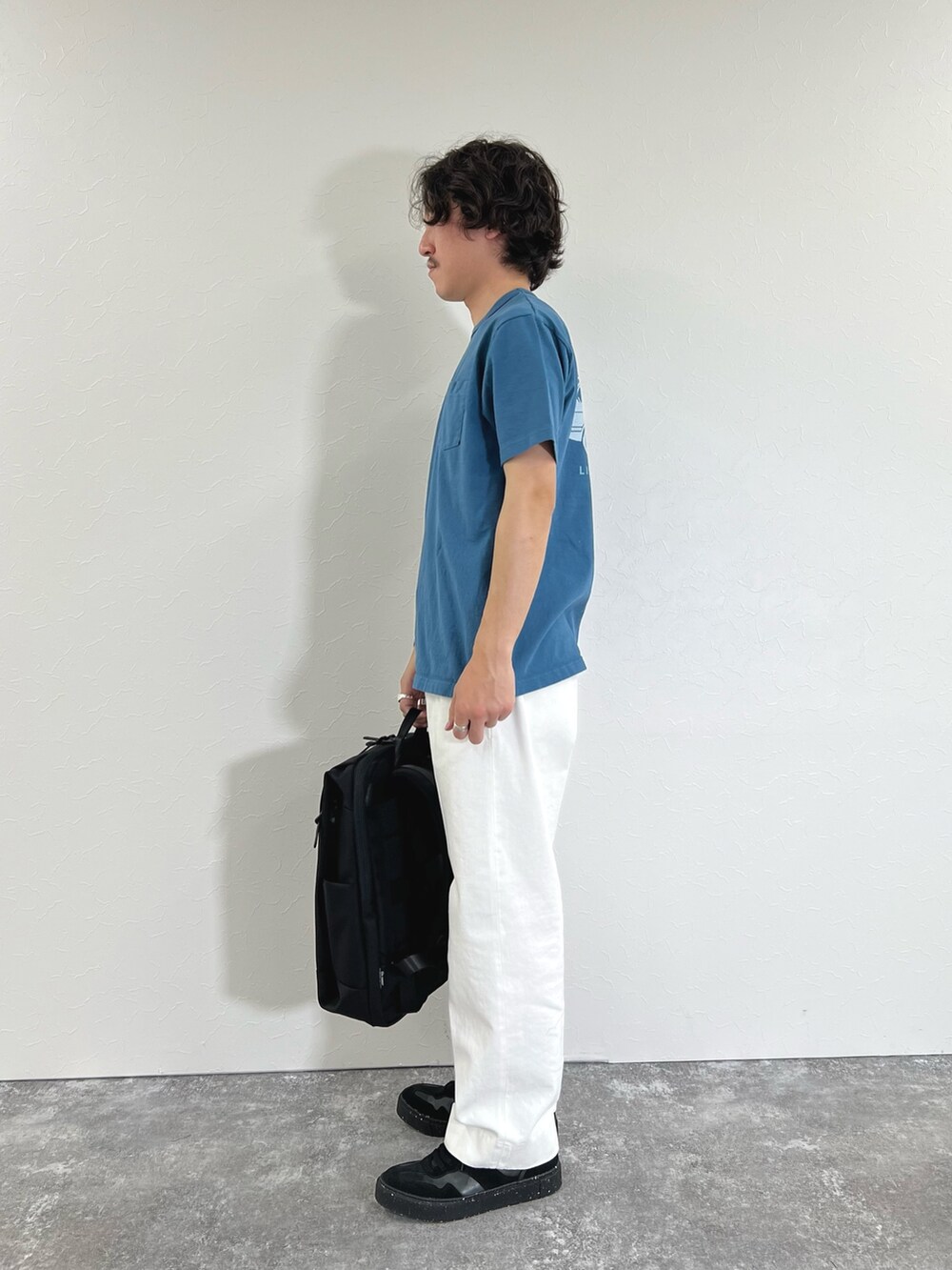 ブルー系のTシャツ/カットソー、ブラック系のショルダーバッグ、ホワイト系のデニムパンツを着用したメンズの春コーディネートの5枚目の写真