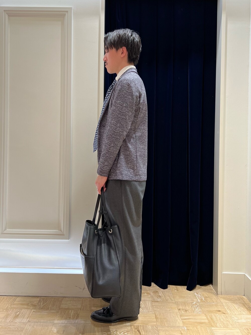 グレー系のカーディガン/ボレロ、ブルー系のネクタイ、ブラック系のトートバッグを着用したメンズの冬コーディネートの3枚目の写真