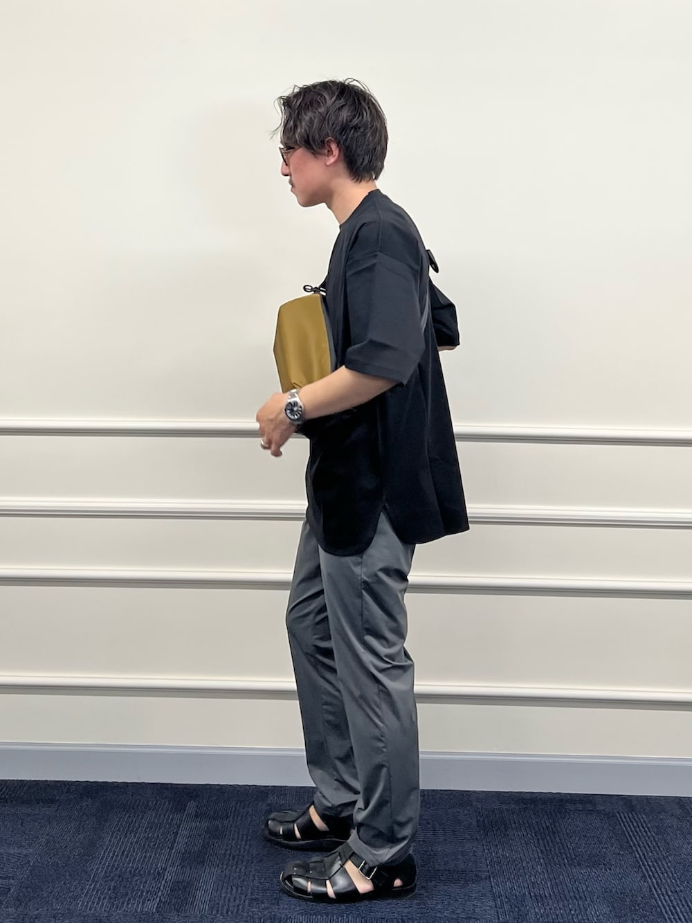 ブラック系のTシャツ/カットソー、グリーン系のショルダーバッグ、グレー系のその他パンツを着用したメンズの春コーディネートの5枚目の写真