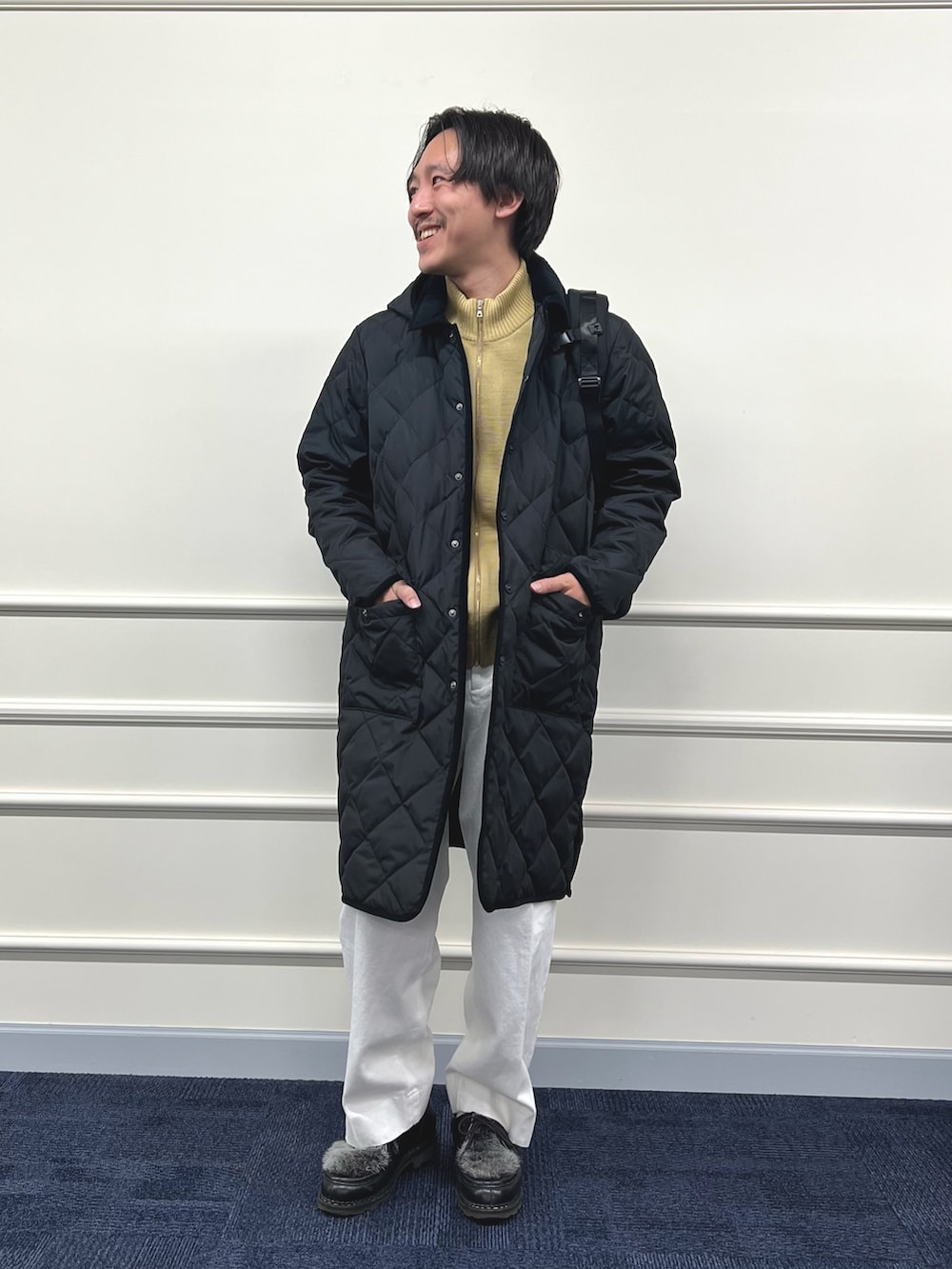 ブラック系のダウンジャケット/コート、ブラック系のバックパック/リュック、ベージュ系のカーディガン/ボレロを着用したメンズの冬コーディネートの4枚目の写真