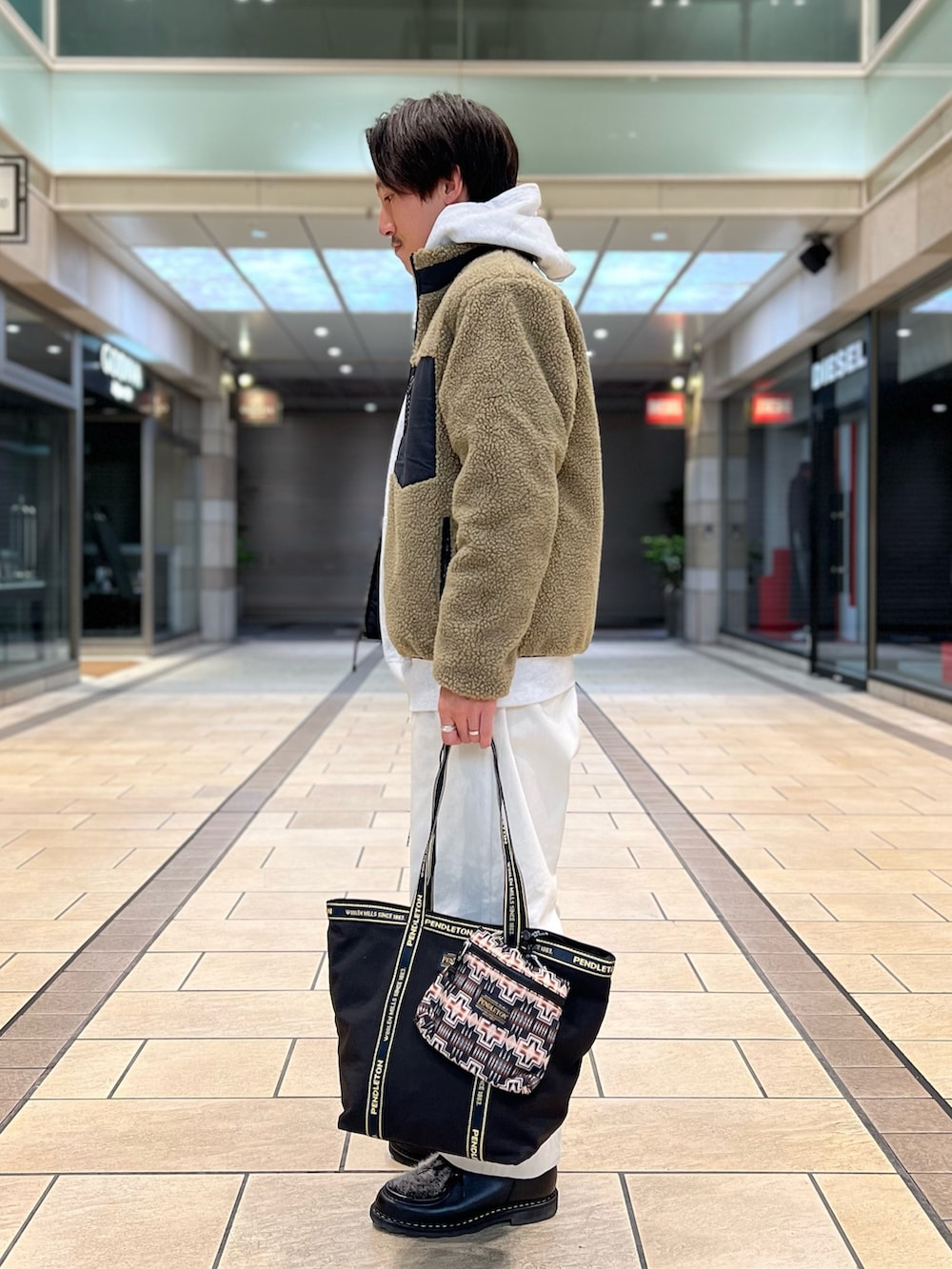 ベージュ系のダウンジャケット/コート、グレー系のパーカー、ブラック系のトートバッグを着用したメンズの秋コーディネートの4枚目の写真