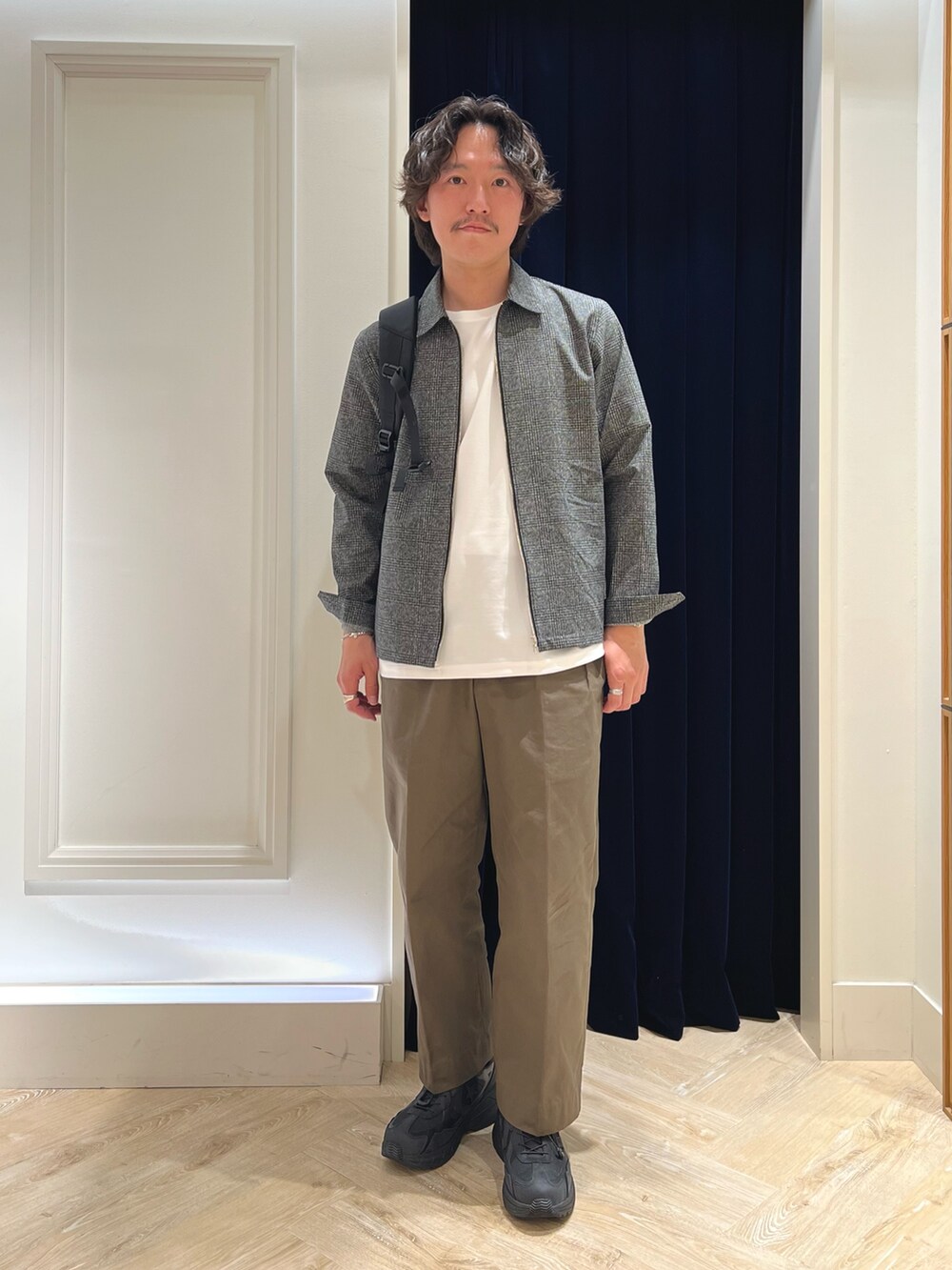 グレー系のブルゾン、ホワイト系のTシャツ/カットソー、ブラック系のバックパック/リュックを着用したメンズの春コーディネートの3枚目の写真