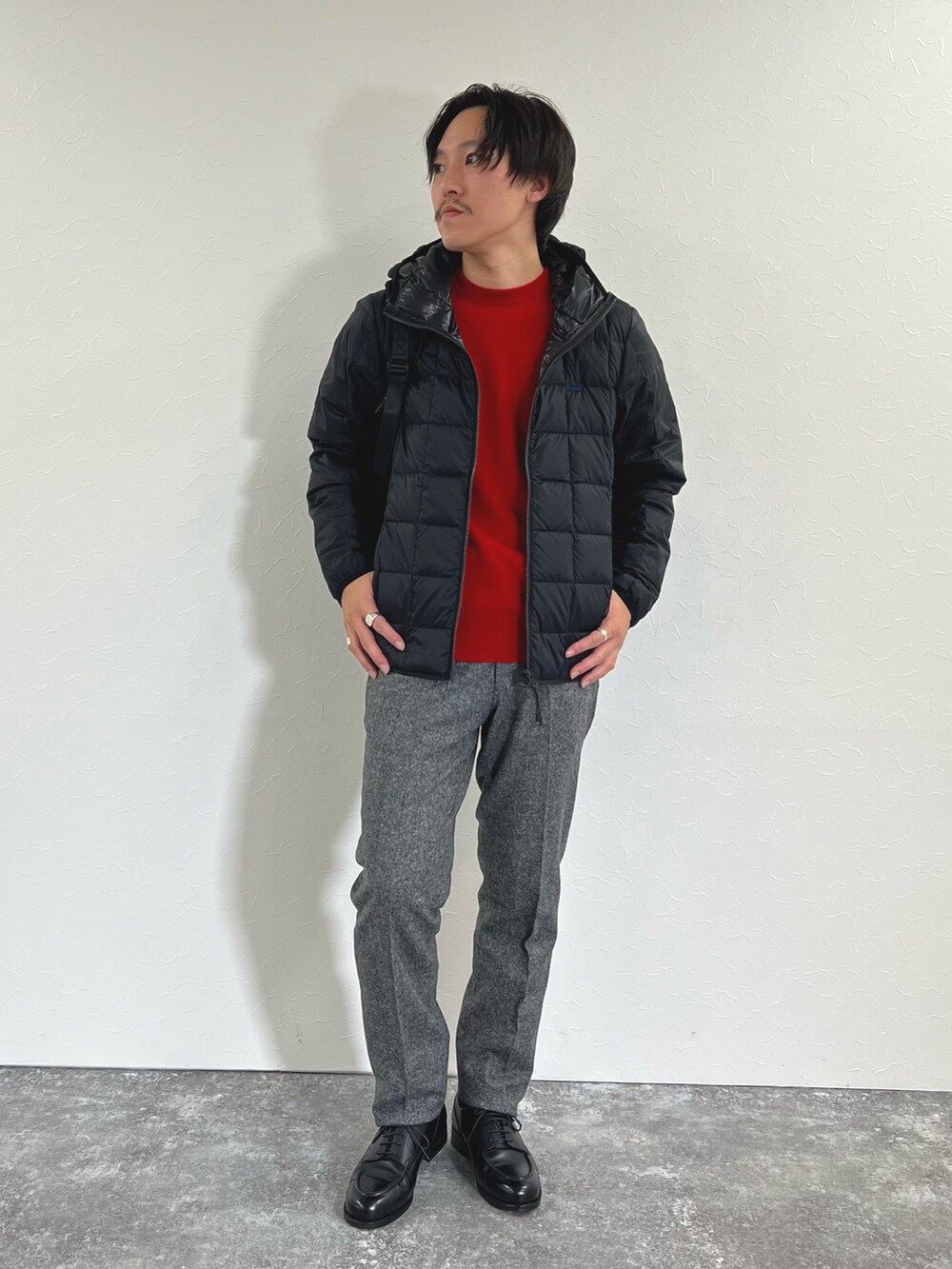 ブラック系のダウンジャケット/コート、レッド系のニット/セーター、グレー系のスラックスを着用したメンズの秋コーディネートの2枚目の写真
