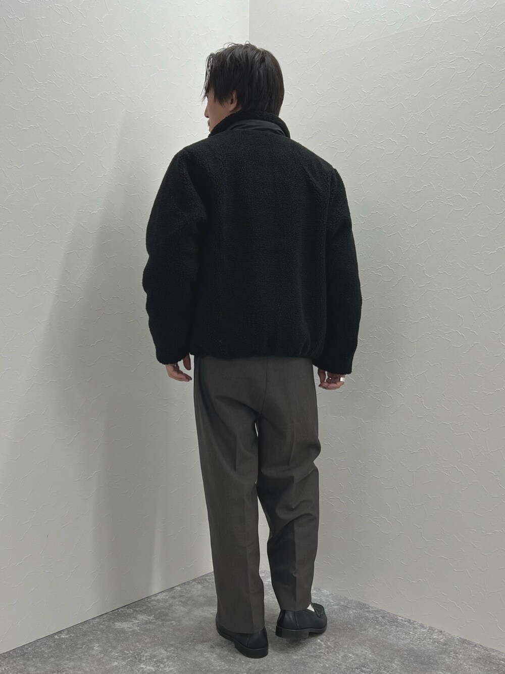 ブラック系のブルゾン、ベージュ系のニット/セーター、グレー系のマフラーを着用したメンズの秋コーディネートの6枚目の写真