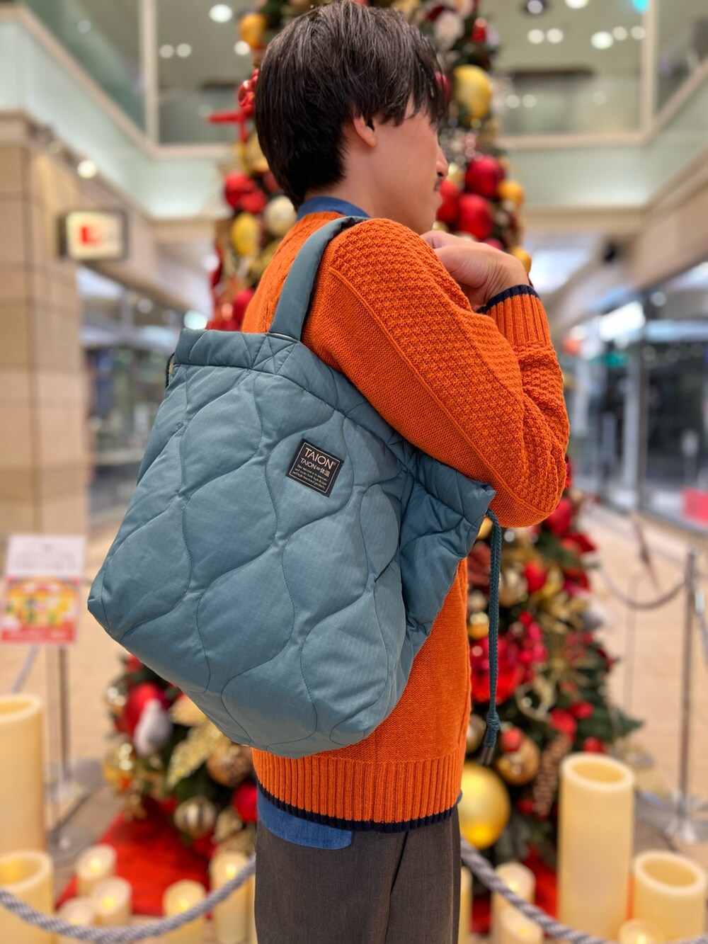 オレンジ系のニット/セーター、ブルー系のシャツ/ブラウス、グリーン系のトートバッグを着用したメンズの冬コーディネートの4枚目の写真