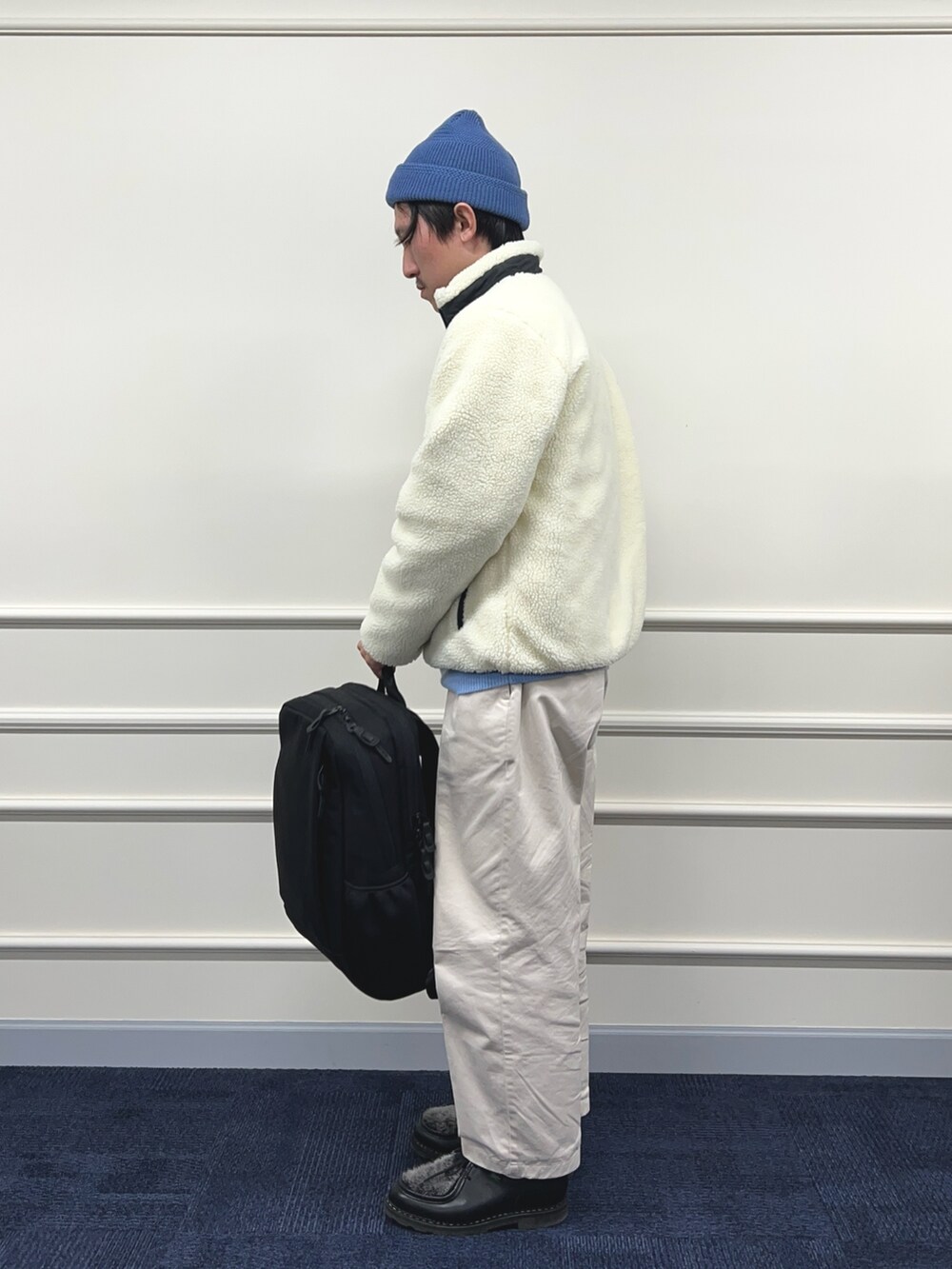 ブルー系のニット/セーター、ホワイト系のブルゾン、ブラック系のバックパック/リュックを着用したメンズの秋コーディネートの5枚目の写真
