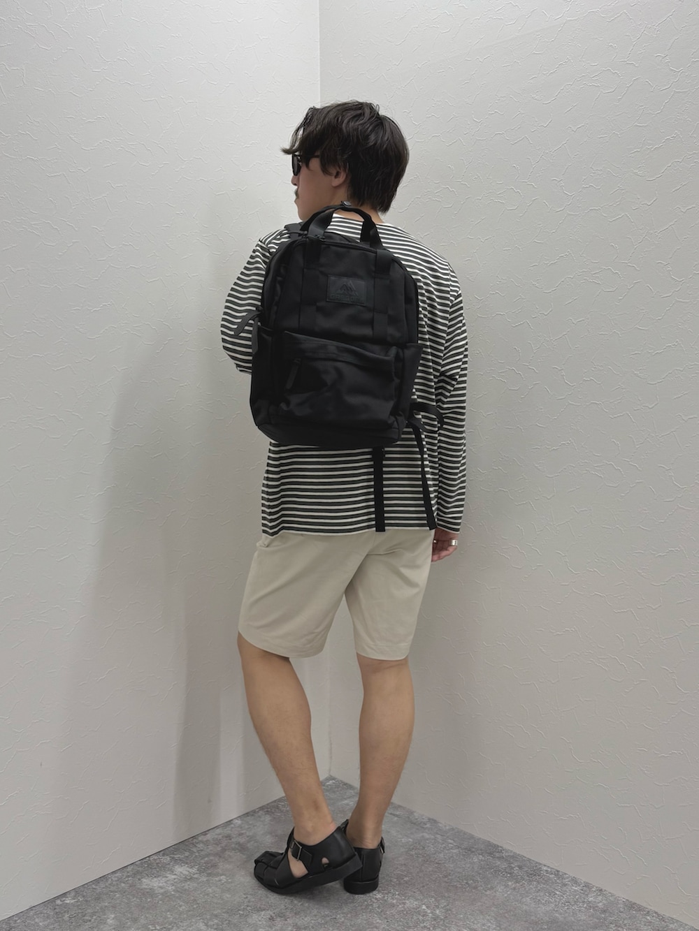 グレー系のTシャツ/カットソー、ホワイト系のその他パンツ、ブラック系のバックパック/リュックを着用したメンズの春コーディネートの4枚目の写真