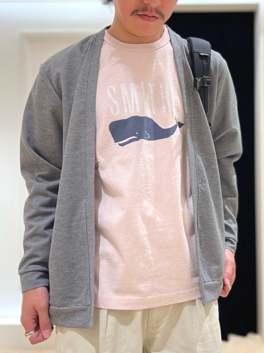 グレー系のカーディガン/ボレロ、ピンク系のTシャツ/カットソー、ブラック系のバックパック/リュックを着用したメンズの春コーディネートの7枚目の写真