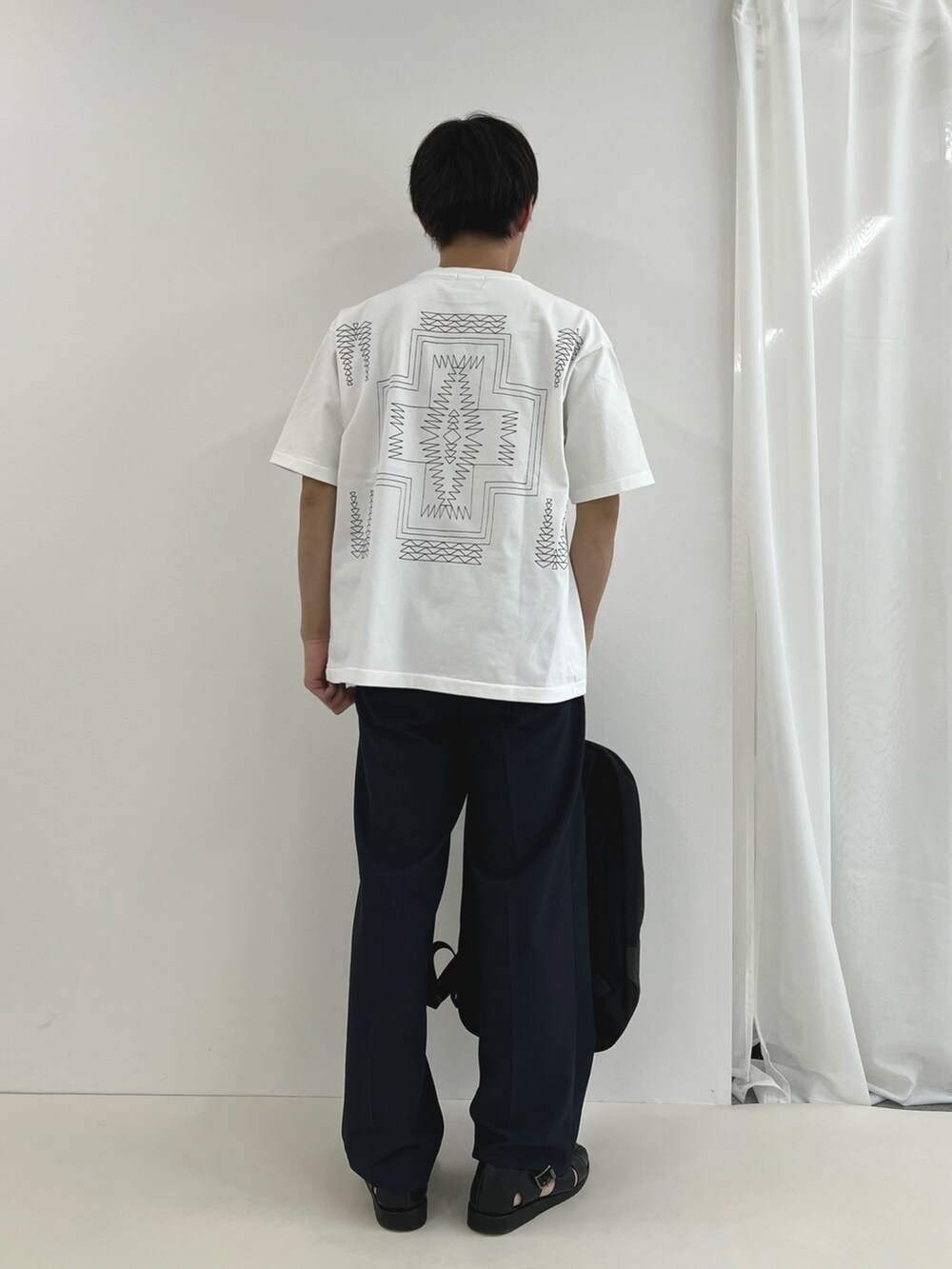 ホワイト系のTシャツ/カットソー、グレー系のバックパック/リュック、ブラック系のその他パンツを着用したメンズの春コーディネートの4枚目の写真