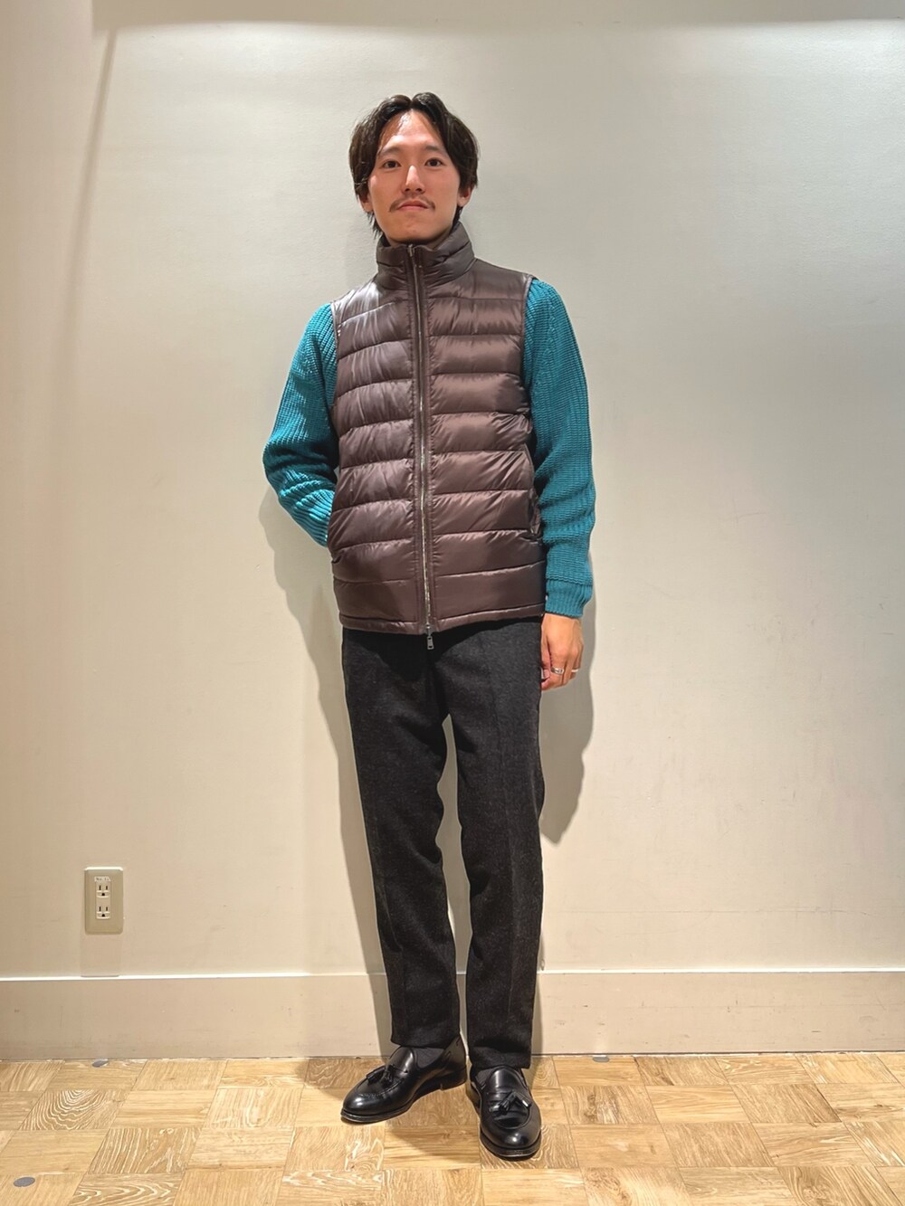 ブラウン系のダウンベスト、ブラック系のハンドバッグを着用したメンズの春コーディネートの6枚目の写真