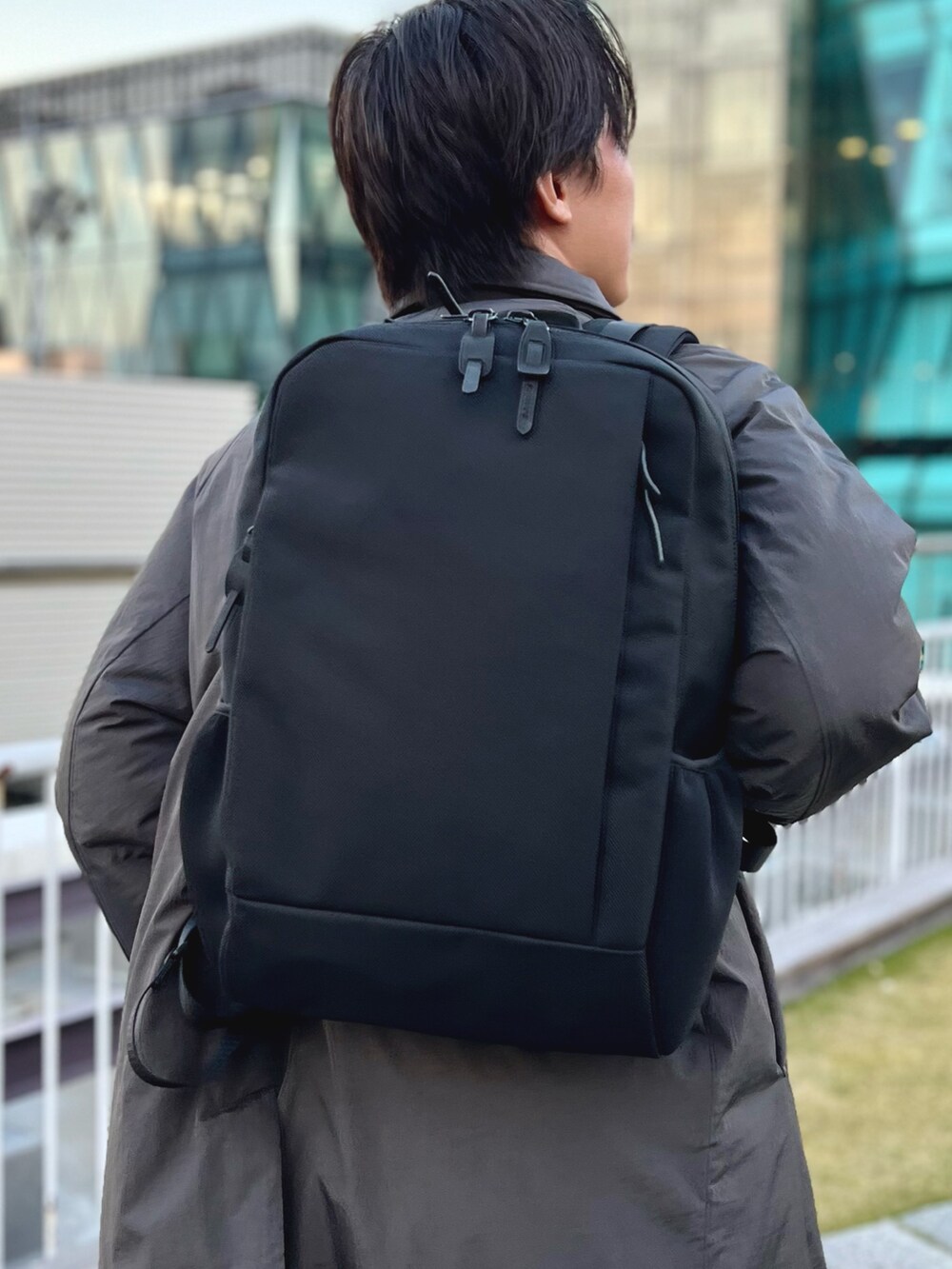 グレー系のダウンジャケット/コート、ブルー系のニット/セーター、ブラック系のバックパック/リュックを着用したメンズの冬コーディネートの7枚目の写真