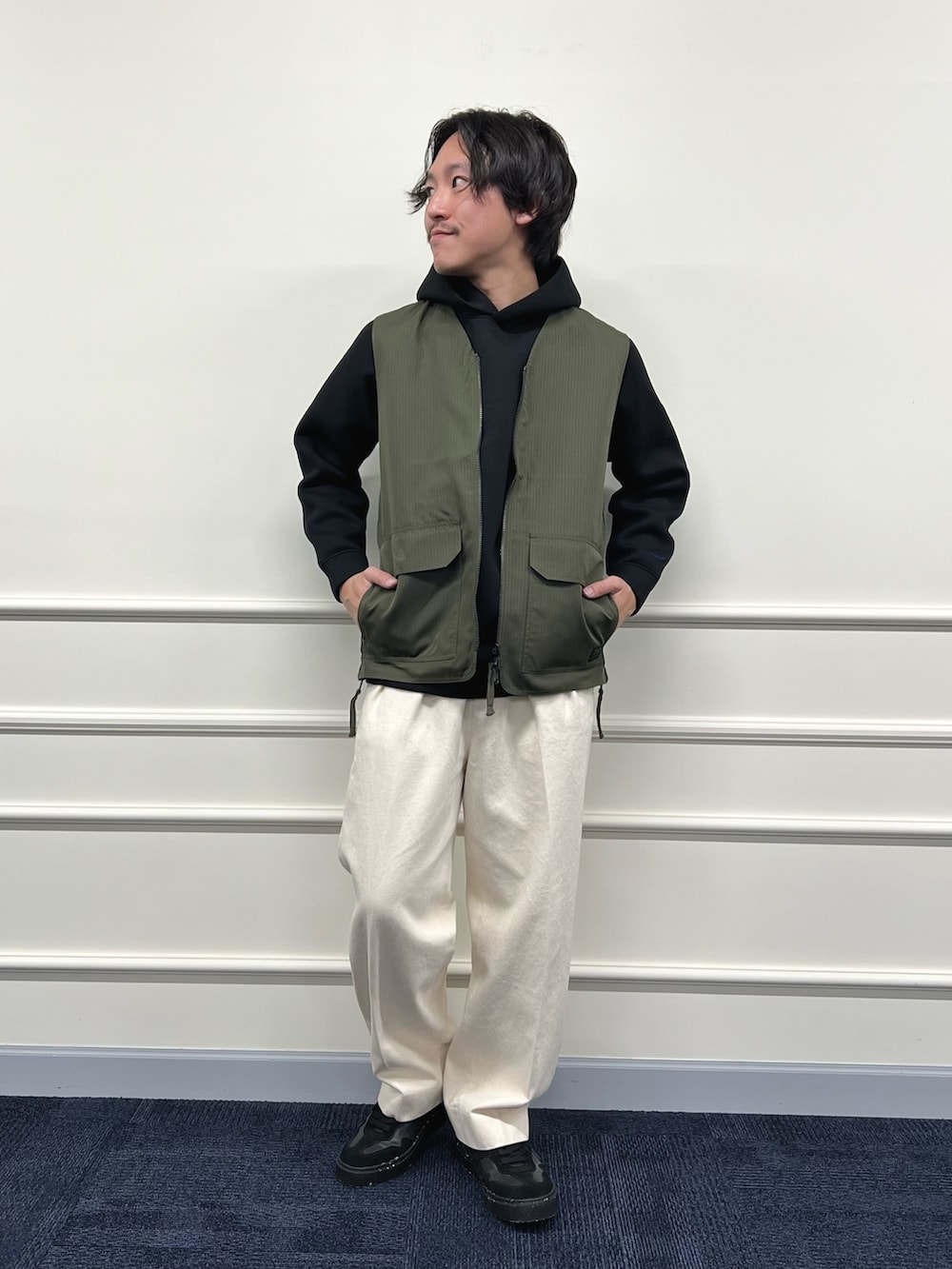 グリーン系のベスト、ブラック系のパーカー、ホワイト系のデニムパンツを着用したメンズの冬コーディネートの4枚目の写真