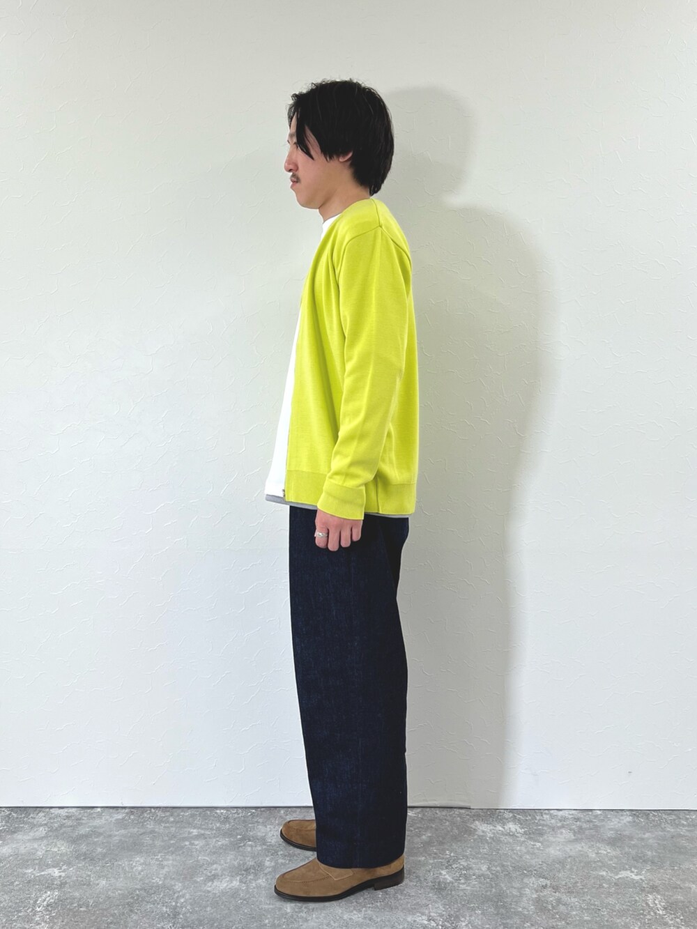 イエロー系のカーディガン/ボレロ、ホワイト系のTシャツ/カットソー、ブルー系のデニムパンツを着用したメンズの冬コーディネートの6枚目の写真