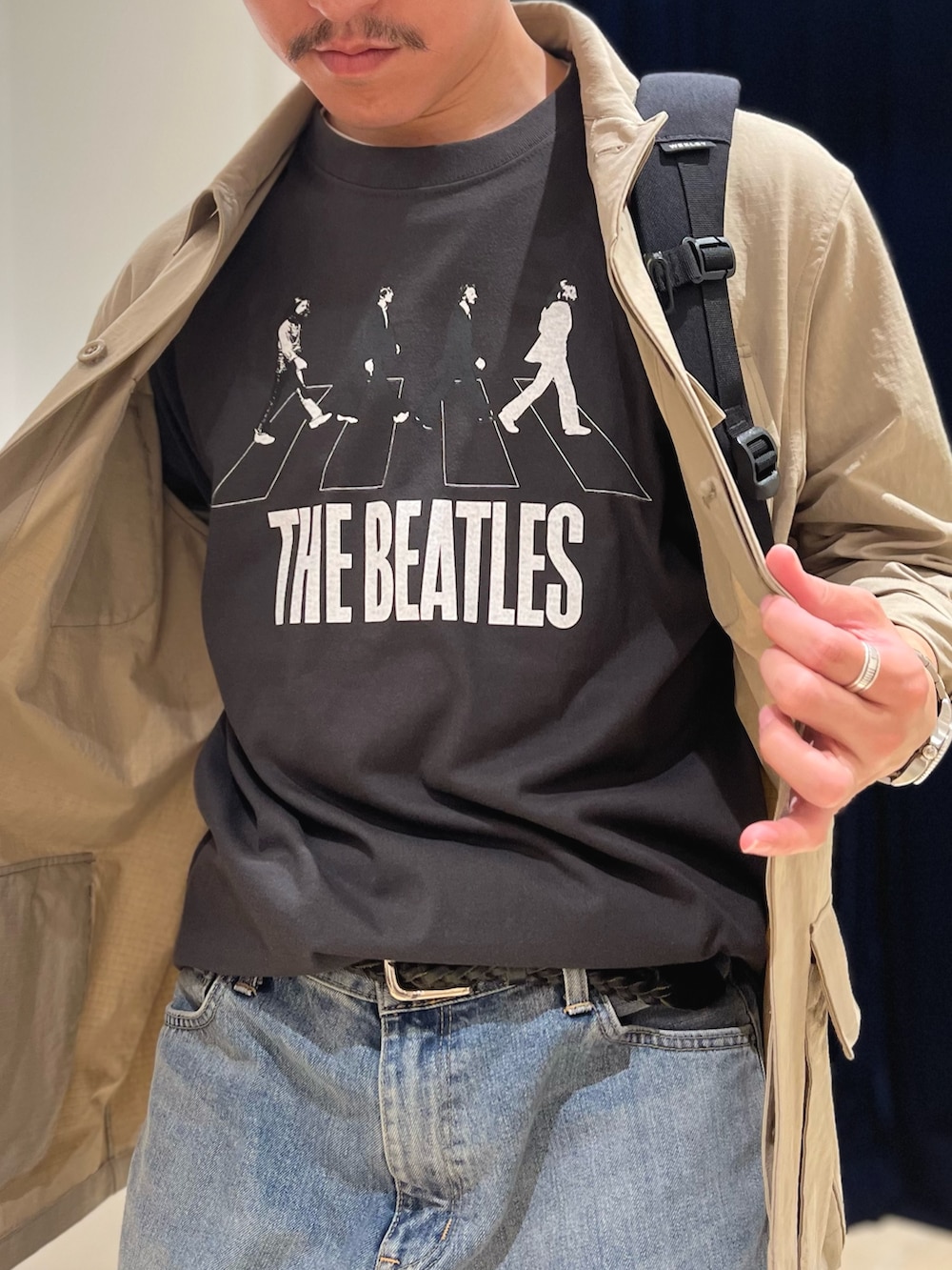 ベージュ系のミリタリージャケット、ブラック系のTシャツ/カットソー、ブラック系のバックパック/リュックを着用したメンズの春コーディネートの9枚目の写真