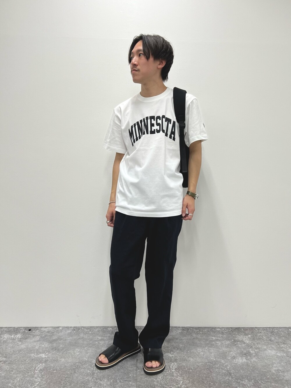 ホワイト系のTシャツ/カットソー、ブラック系のバックパック/リュック、ブラック系のサンダルを着用したメンズの春コーディネートの2枚目の写真