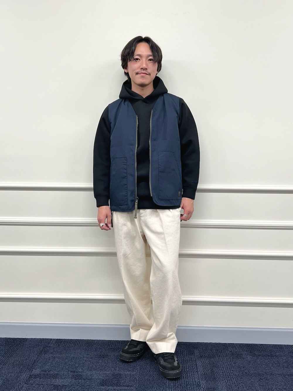 グリーン系のベスト、ブラック系のパーカー、ホワイト系のデニムパンツを着用したメンズの冬コーディネートの3枚目の写真