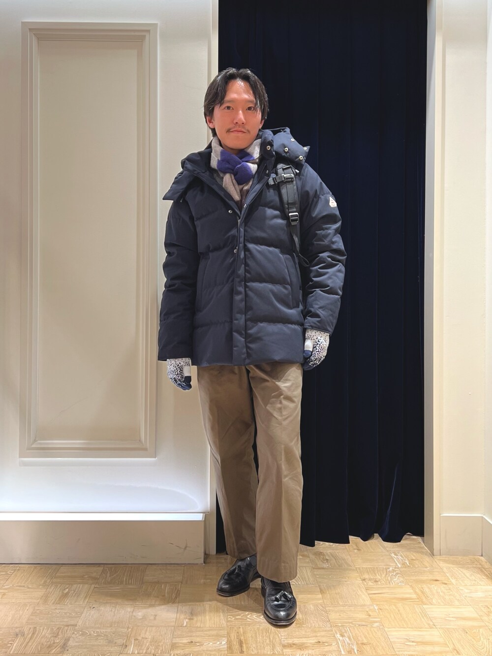 ブルー系のダウンジャケット/コート、ブラック系のバックパック/リュック、グレー系のマフラーを着用したメンズの冬コーディネートの3枚目の写真