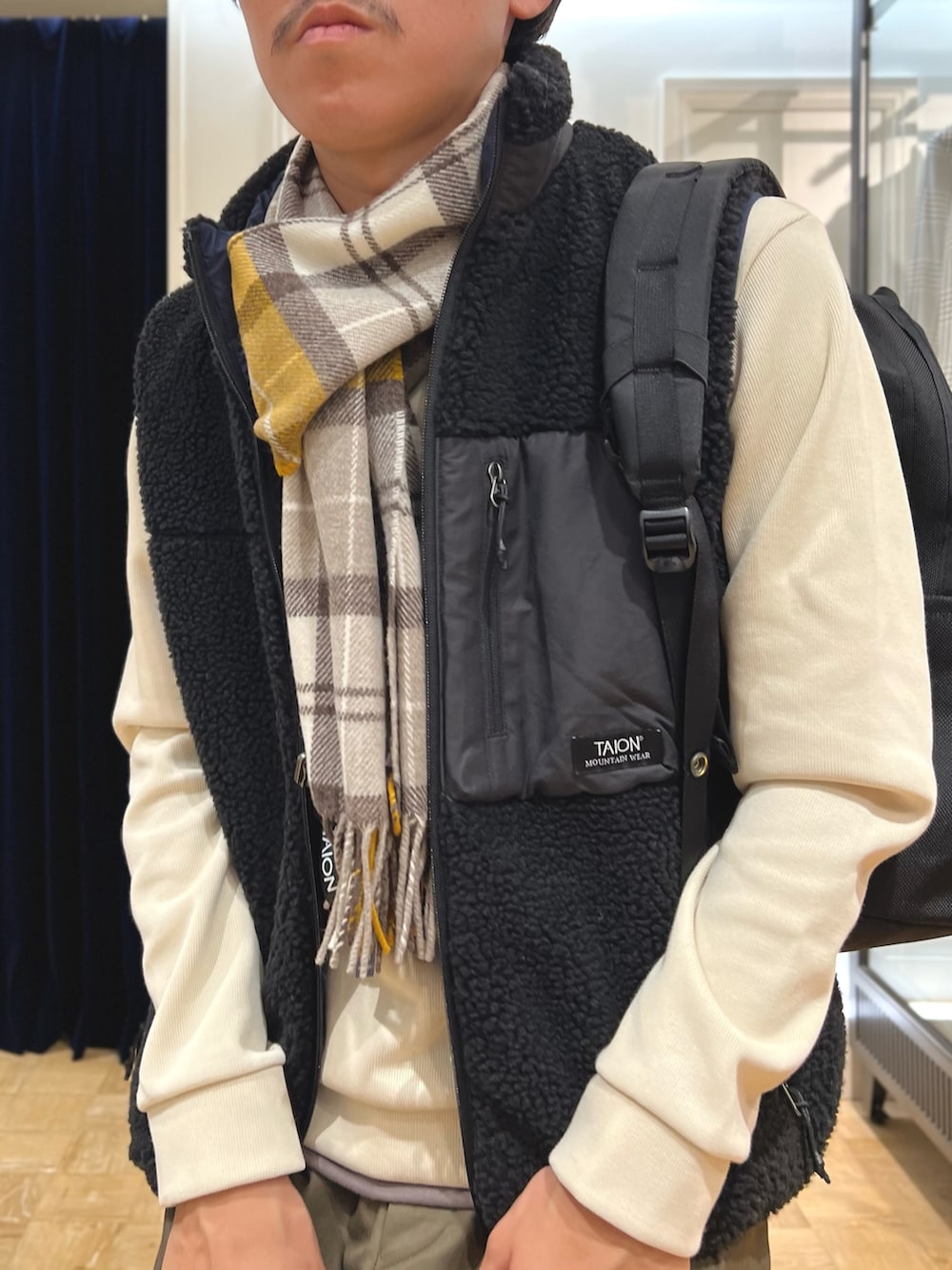 ブラック系のダウンベスト、ホワイト系のTシャツ/カットソー、ブラック系のバックパック/リュックを着用したメンズの秋コーディネートの5枚目の写真